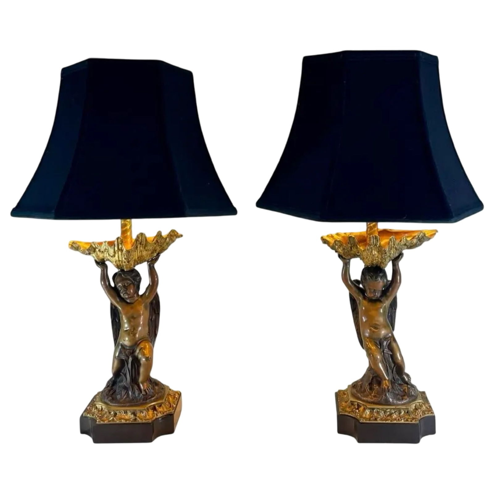 French Bronze Putti Lamps, Pair: French Bronze Putti Lamps, Pair Pair of antique gilt and patinated bronze Leviton corded table lamps with cherub figures supporting large shells on a black stone base. Each lamp is fitted with a navy