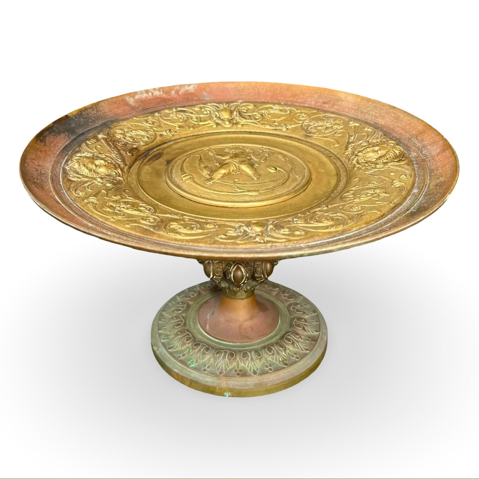 Neoclassical Bronze Cherub Tazza: Bronze tazza with central cherub putto relief and lion head rim. Neoclassical style and Beaux-Arts design influences. Approx. Dimensions: 5.5H x 9.5W x 9.5D inches