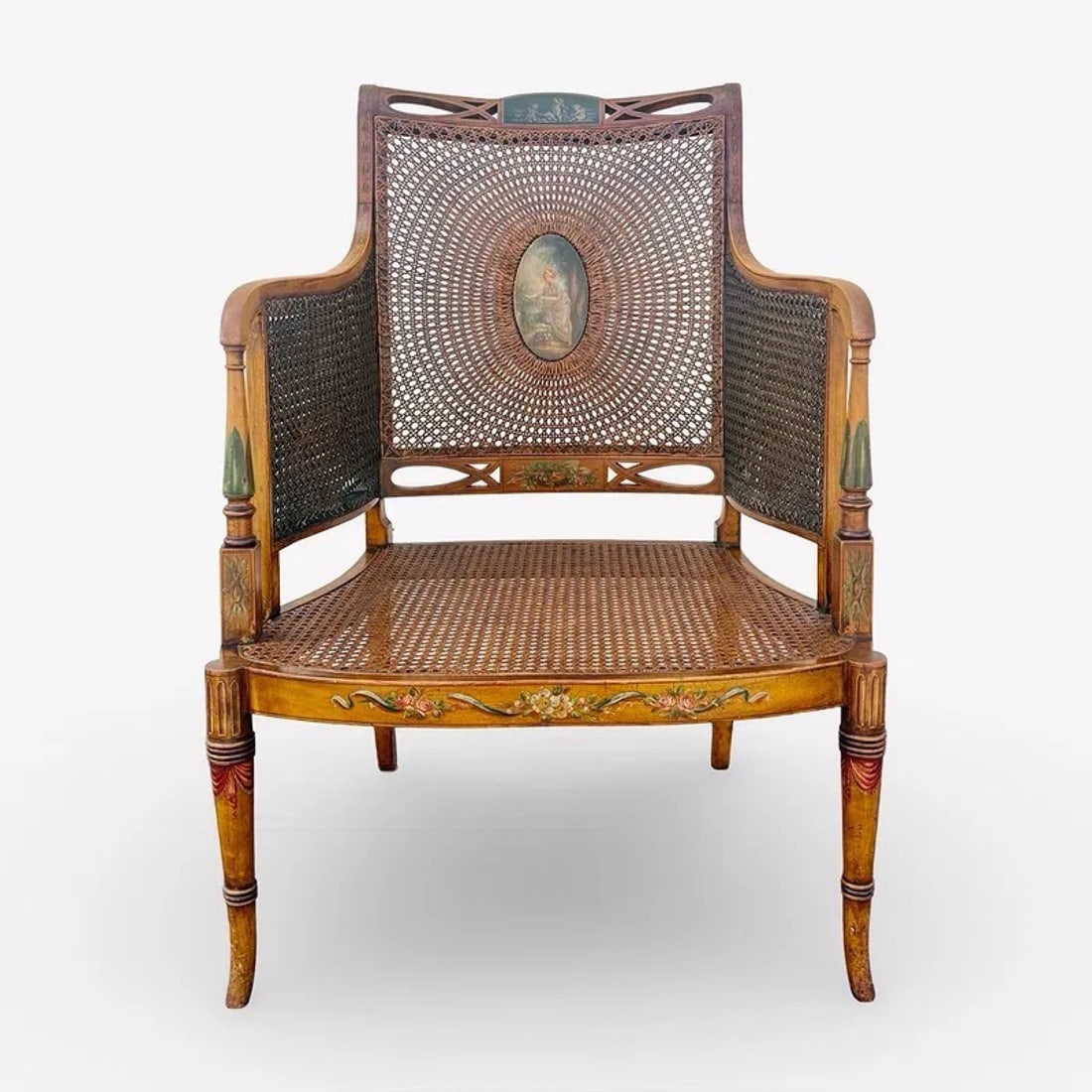 English Regency Bergere Library Armchair: Antique English Regency-style satinwood bergere caned library armchair with painted Neoclassical Sheraton Revival details and wide seat. Includes removable cushion. No reserve. Approx. Dimensions: