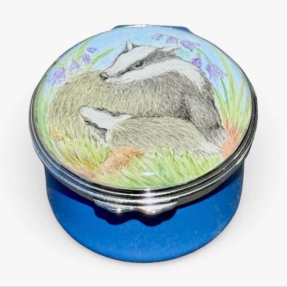 Elliot Hall Badger Wildlife Enamel Trinket Box: Elliot Hall Enamels limited-edition 1/1 trinket box with a badger among flowers on a blue enamel ground. Signed, marked on base, with floral motif on interior of lid. Approx. Dimensions: 1.25H x 1.5W 