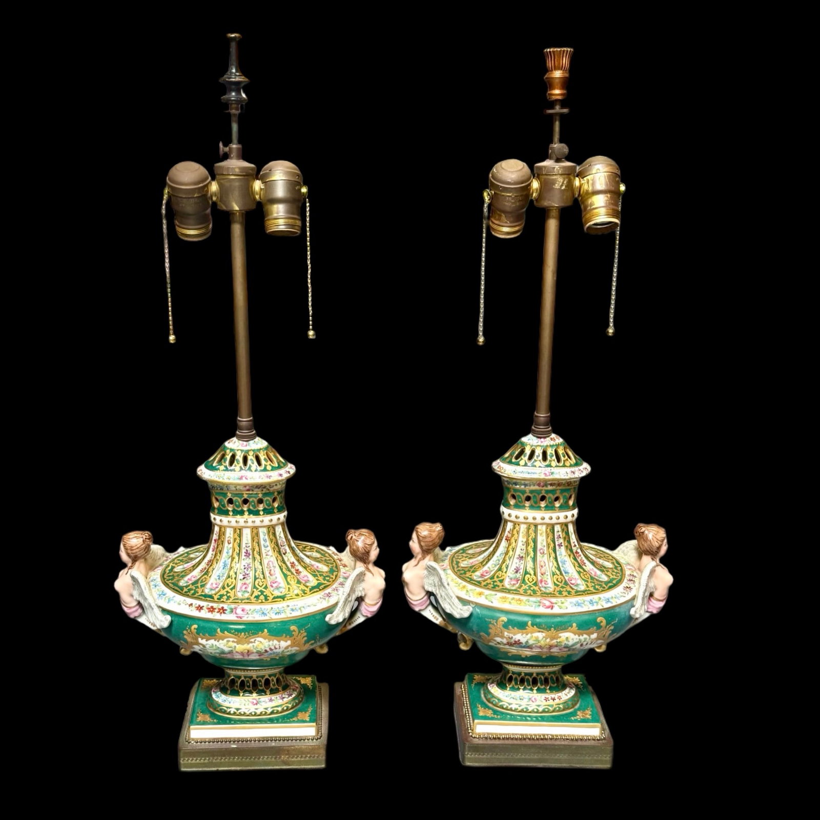 Neoclassical Porcelain Urn Lamps Pair: Pair of Neoclassical porcelain table lamps with twin-handled urn forms, figural winged siren handles, emerald green glaze, hand-painted floral decoration, and extensive gilt detailing. Mounted with br