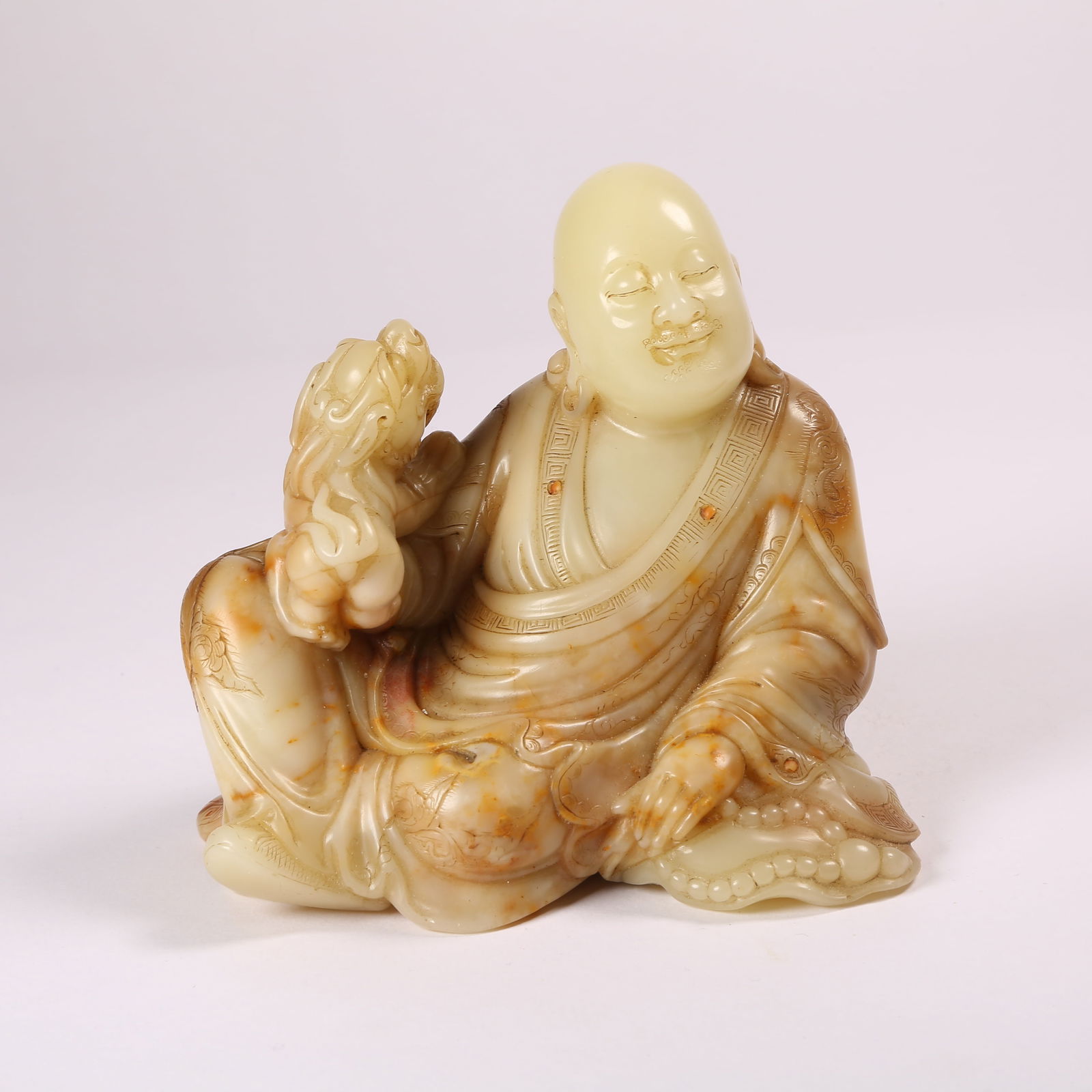 A POLYCHROME SHOUSHAN STONE RECLINING TIGER SEATED ARHAT: Polychrome Shoushan Stone Reclining Tiger Seated Arhat