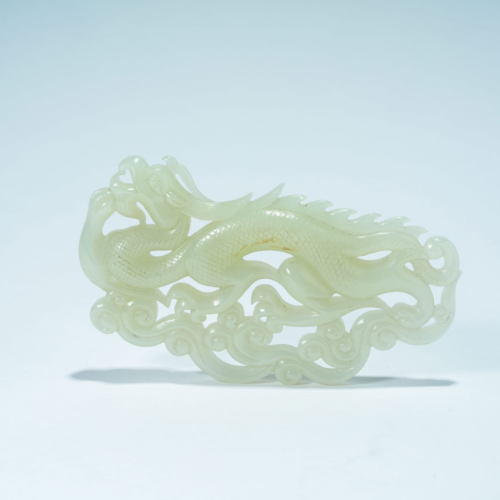 A HETIAN JADE CARVED PENDANT WITH CLOUD-AND-DRAGON DESIGN: Hetian Jade Carved Pendant with Cloud-and-Dragon Design