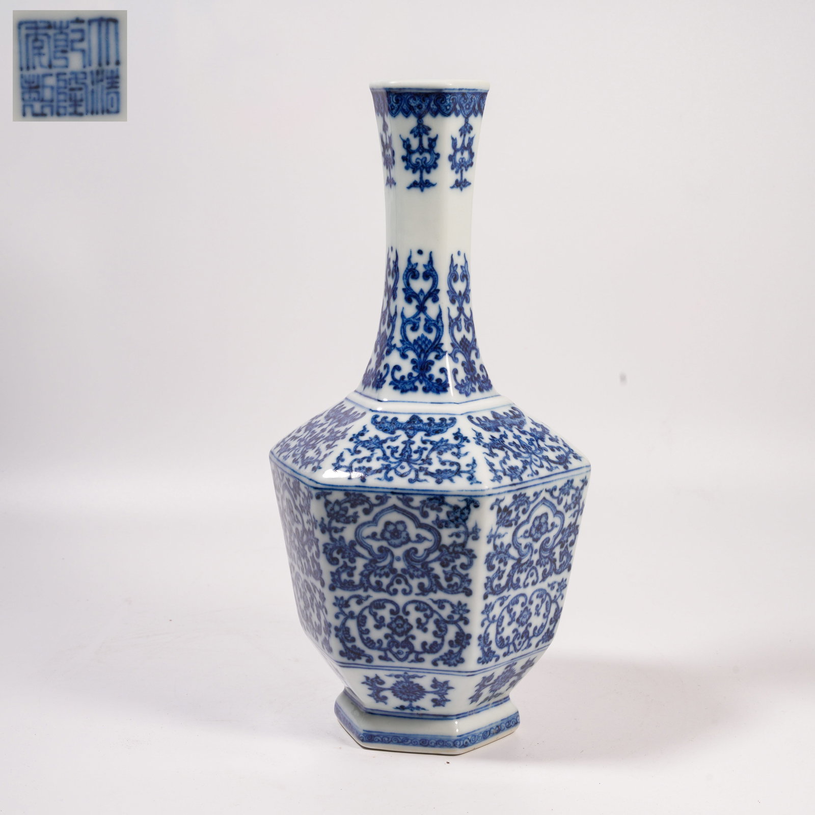 A BLUE-AND-WHITE HEXAGONAL LONG-NECK VASE WITH INTERTWINING FLORAL SCROLLS: Blue-and-White Hexagonal Long-Neck Vase with Intertwining Floral Scrolls