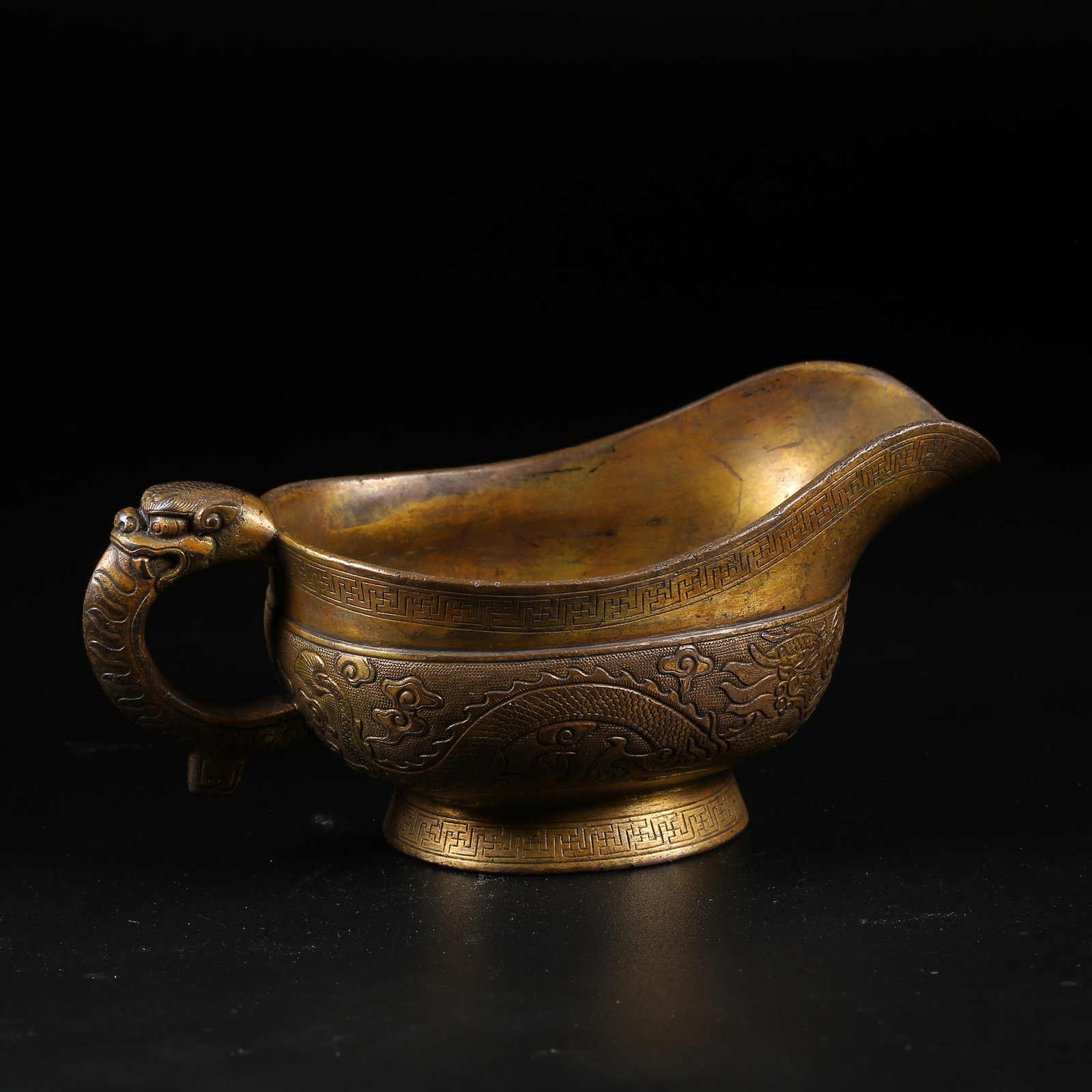A GILT-BRONZE BEAST-HANDLED JUE CUP WITH CLOUD AND DRAGON CHASING PEARL PATTERN: Gilt-Bronze Beast-Handled Jue Cup with Cloud and Dragon Chasing Pearl Pattern
