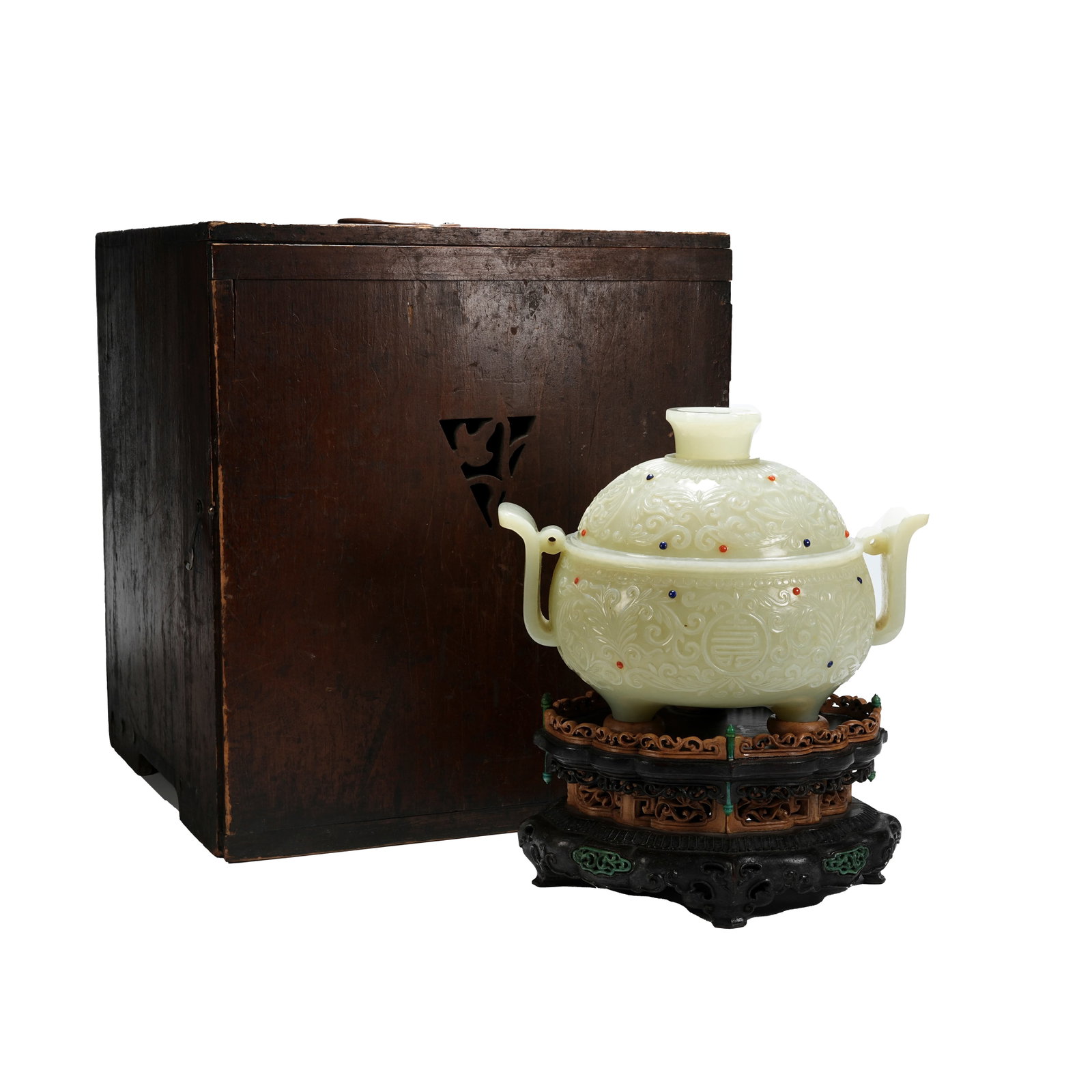HETIAN WHITE JADE MUGHAL-STYLE GEM-INLAID INTERLOCKING FLORAL ROUND SHOU PATTERN THREE-LEGGED CENSER: Qing Dynasty Hetian white jade three-legged lidded censer with court hat-shaped ears carved in Mughal style and inlaid gem interlocking round longevity patterns, complete with original wooden stand