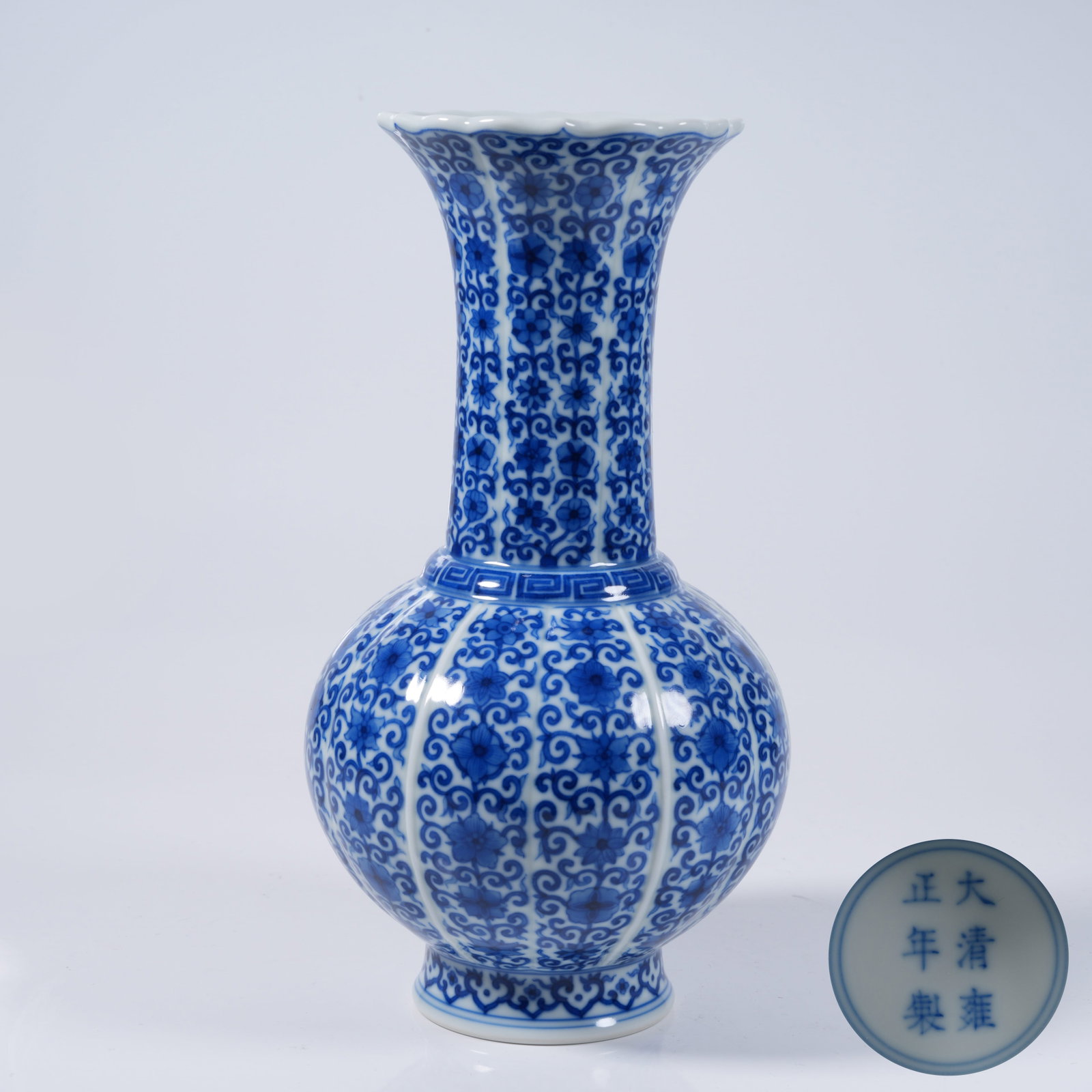 A BLUE AND WHITE LONG-NECKED FLOWER-MOUTH VASE WITH INTERLOCKING FLORAL PATTERN: Blue and White Long-necked Flower-mouth Vase with Interlocking Floral Pattern