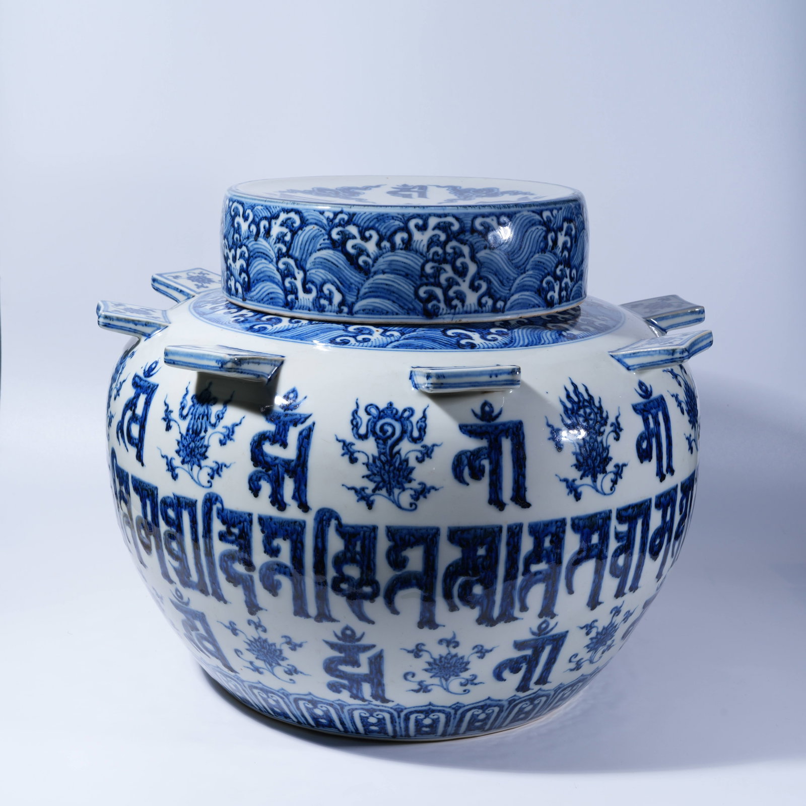A BLUE AND WHITE COVERED JAR WITH WING EARS AND SANSKRIT INSCRIPTION ON BLUE GROUND: Blue and White Covered Jar with Wing Ears and Sanskrit Inscription on Blue Ground