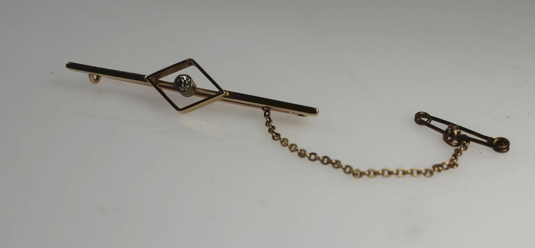 GEOMETRIC-DESIGN DIAMOND BAR BROOCH IN 15CT YELLOW GOLD WITH SAFETY CHAIN: Geometric-design Diamond Bar Brooch in 15ct Yellow Gold with Safety Chain