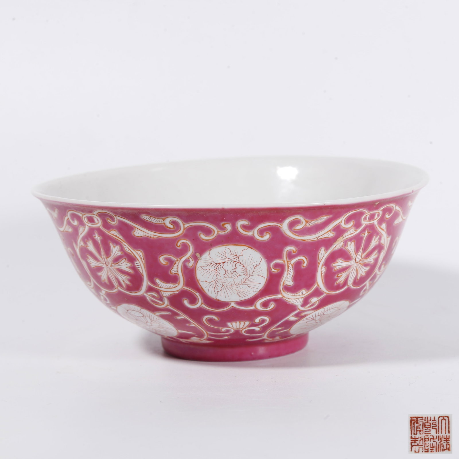 A CARMINE-GROUND FAMILLE ROSE BOWL WITH INTERLOCKING FLORAL SCROLLS: Carmine-ground famille rose bowl with interlocking floral scrolls