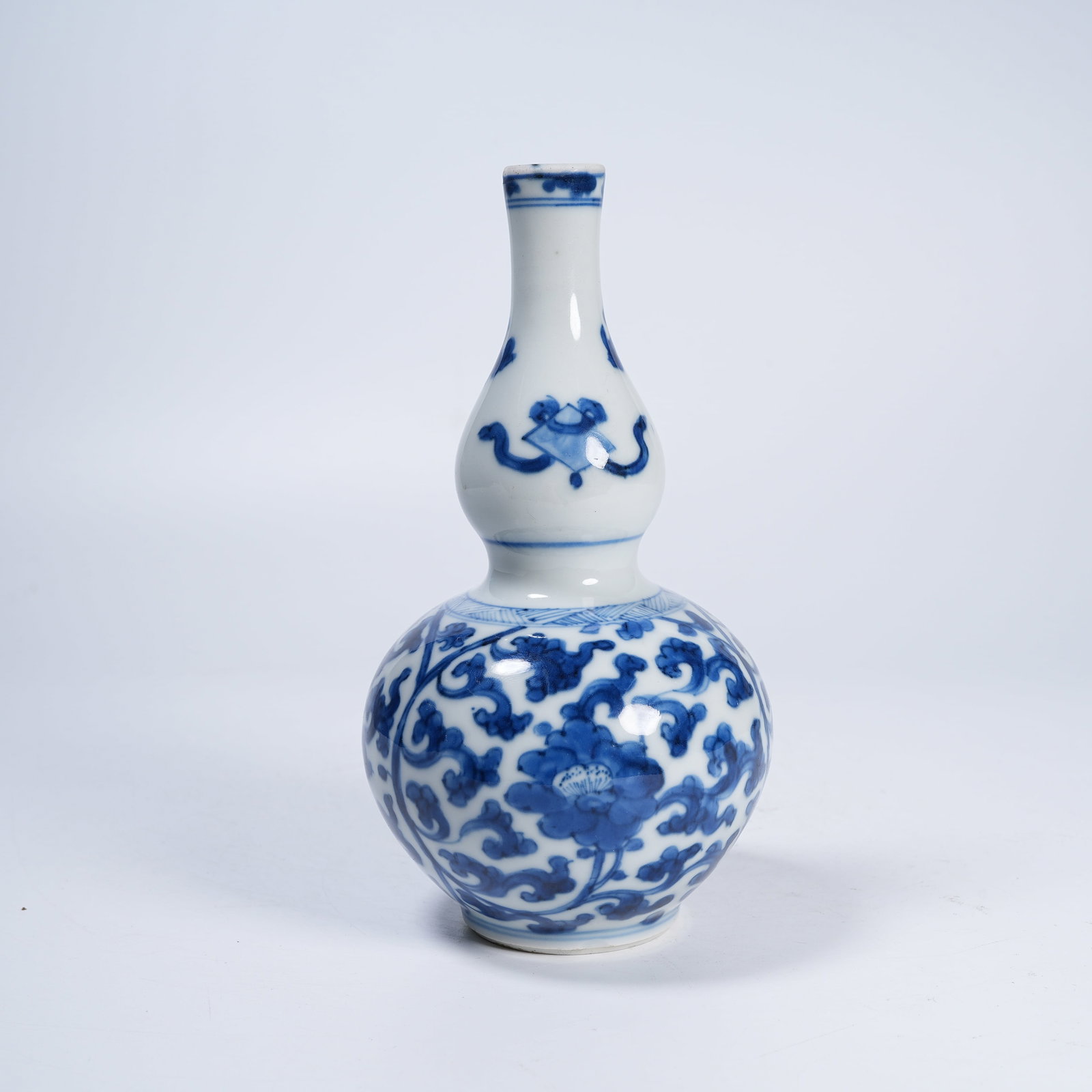 A BLUE AND WHITE GOURD VASE WITH INTERLOCKING SCROLLS: Blue and White Gourd Vase with Interlocking Scrolls