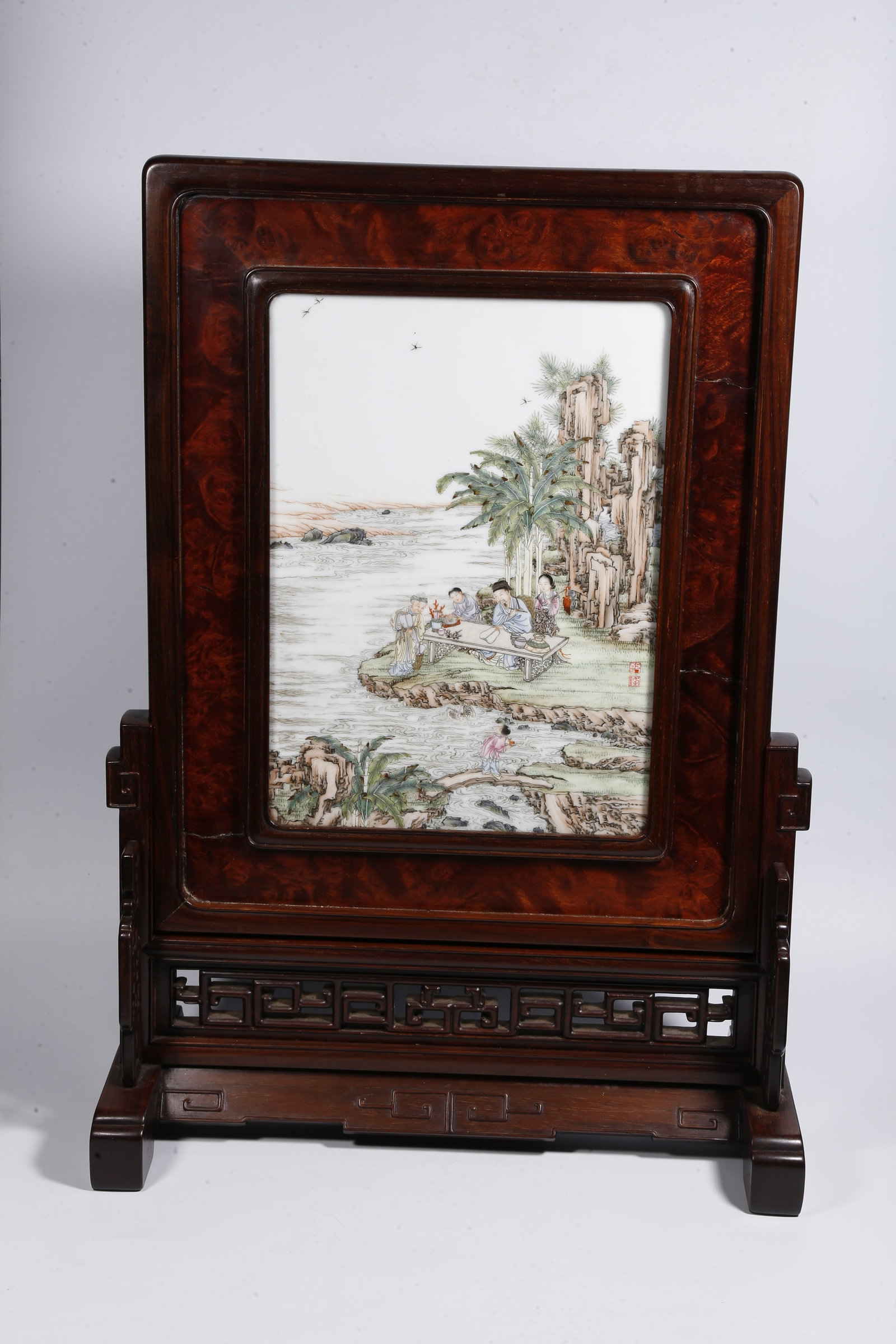 A HUANGHUALI WOOD TABLE SCREEN INLAID WITH FAMILLE ROSE NARRATIVE FIGURE PORCELAIN PANEL: Huanghuali Wood Table Screen Inlaid with Famille Rose Narrative Figure Porcelain Panel