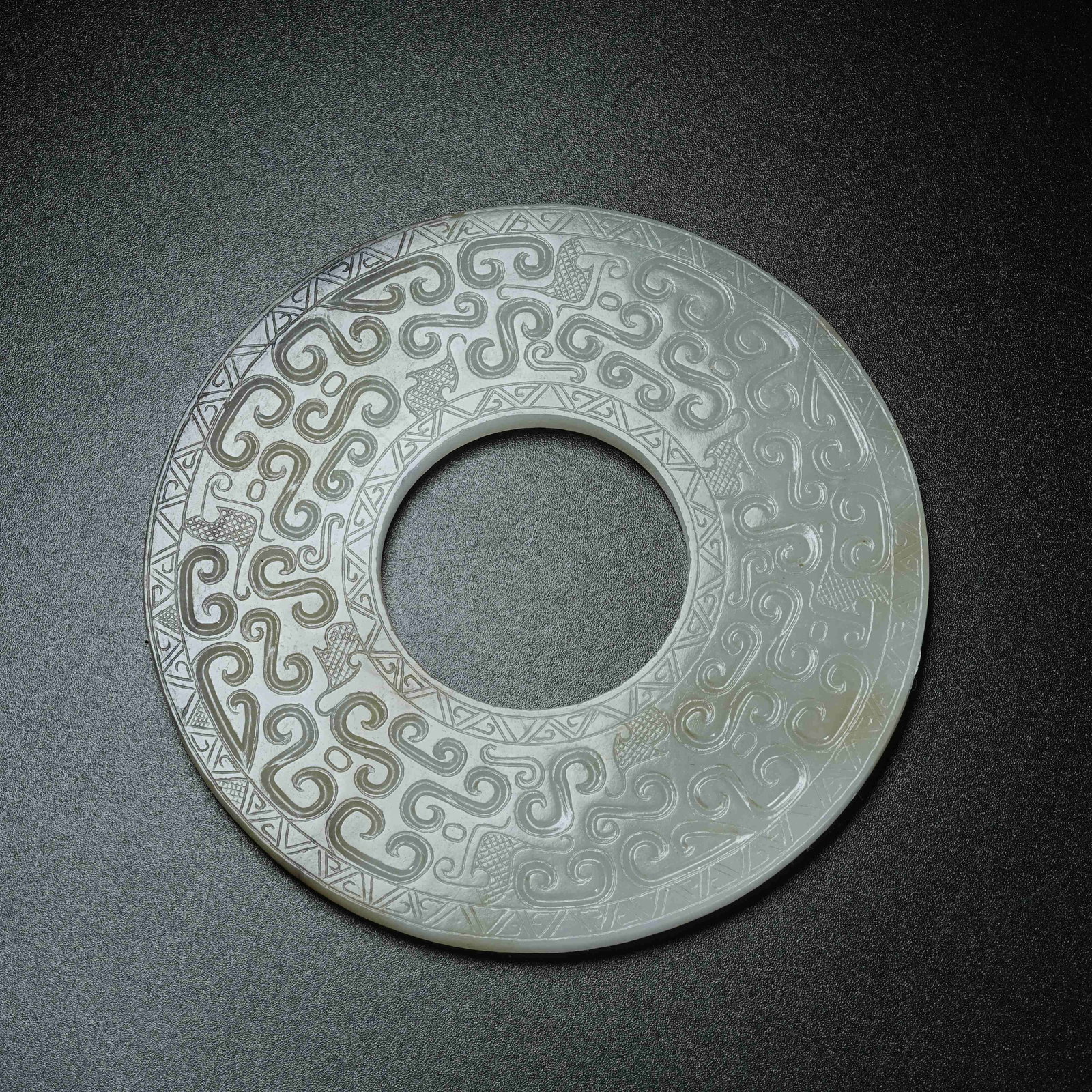 A ARCHAIC JADE BI DISC WITH HOOKED CLOUD PATTERN: Archaic Jade Bi Disc with Hooked Cloud Pattern