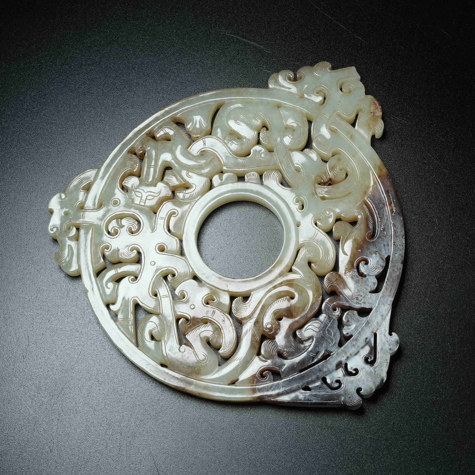 A ANCIENT JADE OPENWORK BI DISC CARVED WITH CHI DRAGON PATTERNS EXTENDING BEYOND RIM: Ancient Jade Openwork Bi Disc Carved with Chi Dragon Patterns Extending Beyond Rim