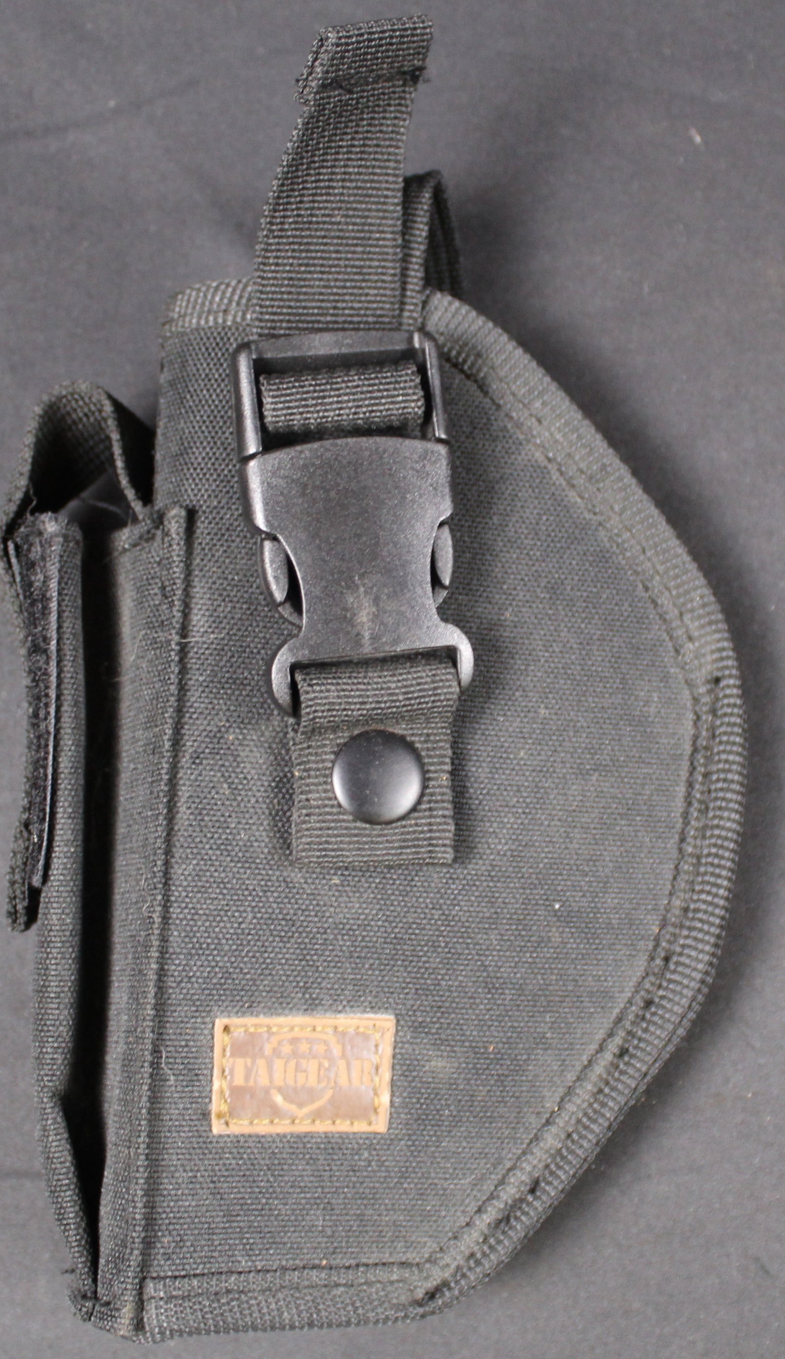 TAIGEAR Nylon Pistol Holster (DMS): This TAIGEAR Nylon Pistol Holster is in good condition showing some signs of wear on the buckles and the strapping. Bidders are welcome to preview items in person during our normal operating hours Tue