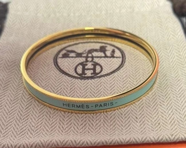 Hermès Enamel and Gold Plated Bangle Light Blue: Elegant Hermès enamel bangle bracelet in a vibrant light blue with gold-plated metal, a clean pop of color that works beautifully alone or stacked. Includes pouch + box. Highlights Brand: Hermès