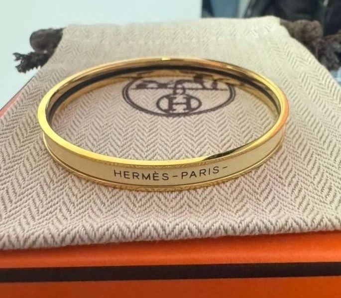 Hermès Enamel and Gold Plated Bangle Beige: Timeless Hermès enamel bangle bracelet in a versatile beige tone with gold-plated metal. Neutral, elegant, and easy to style year-round, especially strong as a stacking piece. Includes pouch. 