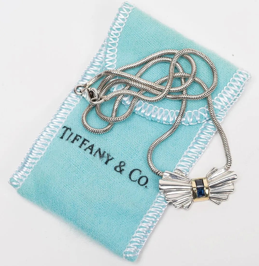 Tiffany & Co Art Deco 18K Gold & Sterling Silver Tie Bow Necklace: Tiffany & Co Art Deco 18K Gold & Sterling Tie Bow Necklace Offered is a Tiffany & Co. Art Deco-era style tie-bow necklace featuring a sculptural bow motif with two bezel-set, square faceted sapphire g