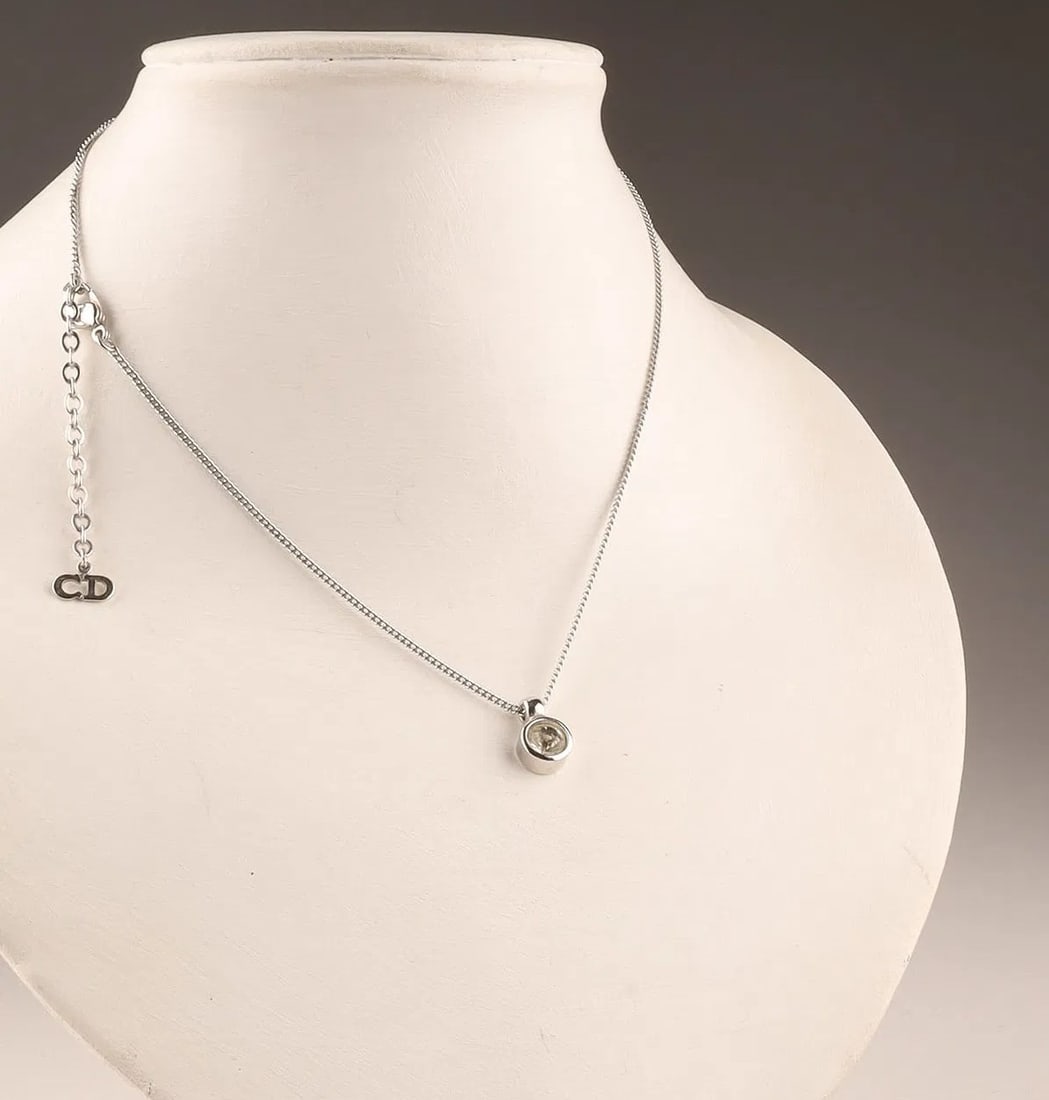 Christian Dior Round Faceted CZ Pendant Necklace 18" + CD Tag: Christian Dior Round Faceted CZ Pendant Necklace Offered is a Christian Dior pendant necklace featuring a round, faceted cubic zirconia-style center stone and a Dior "CD" hangtag accent. The look is c