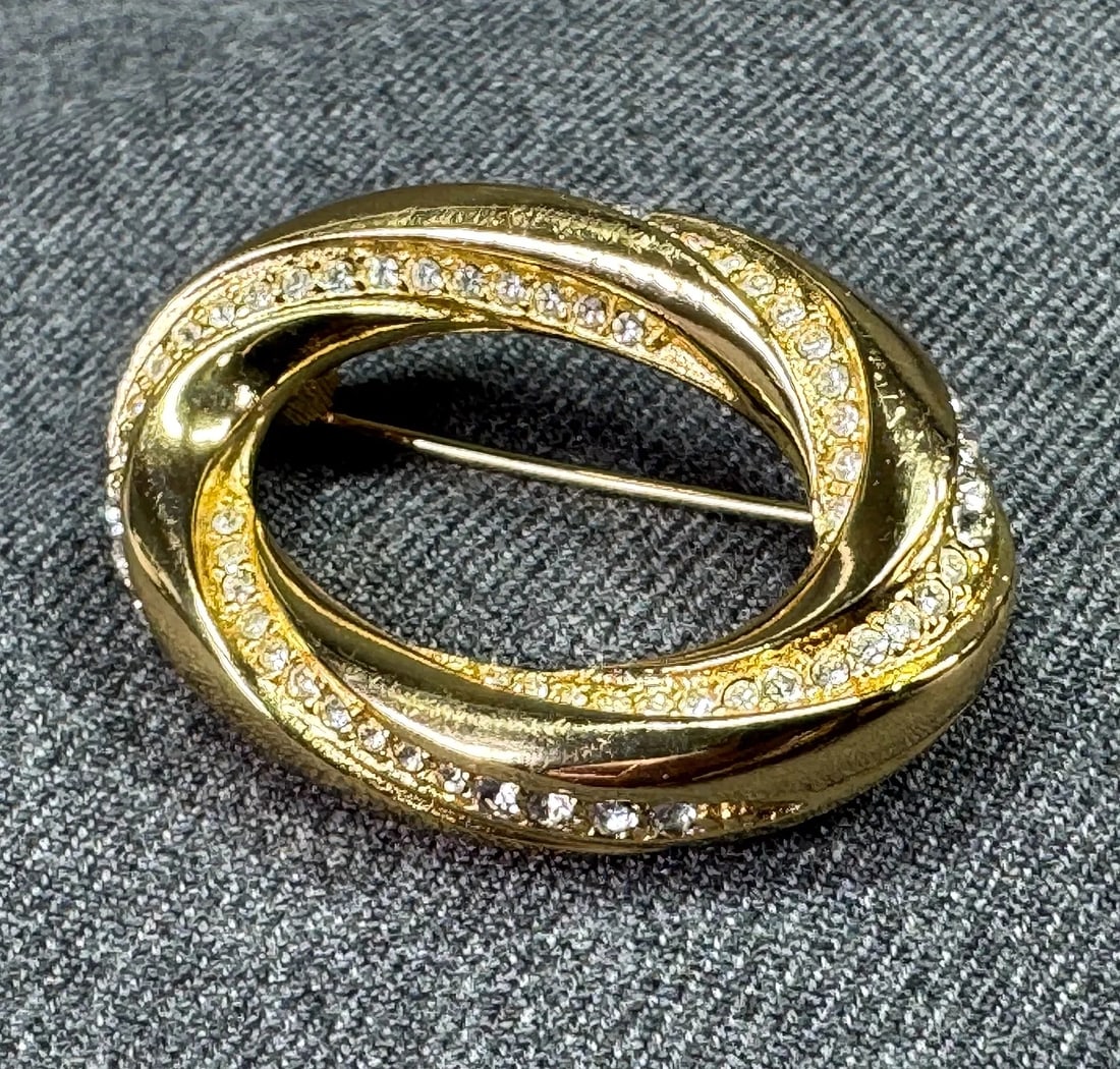 Christian Dior Vintage Oval Swirl Brooch in Gold-Tone w/ clear Rhinestones 17 g 1.5 x 1 in w/ Box: Striking vintage Christian Dior oval swirl brooch in gold-tone metal set with clear rhinestones, a classic couture sparkle piece that elevates any blazer, dress, or scarf. Comes with box. Highlgihts D