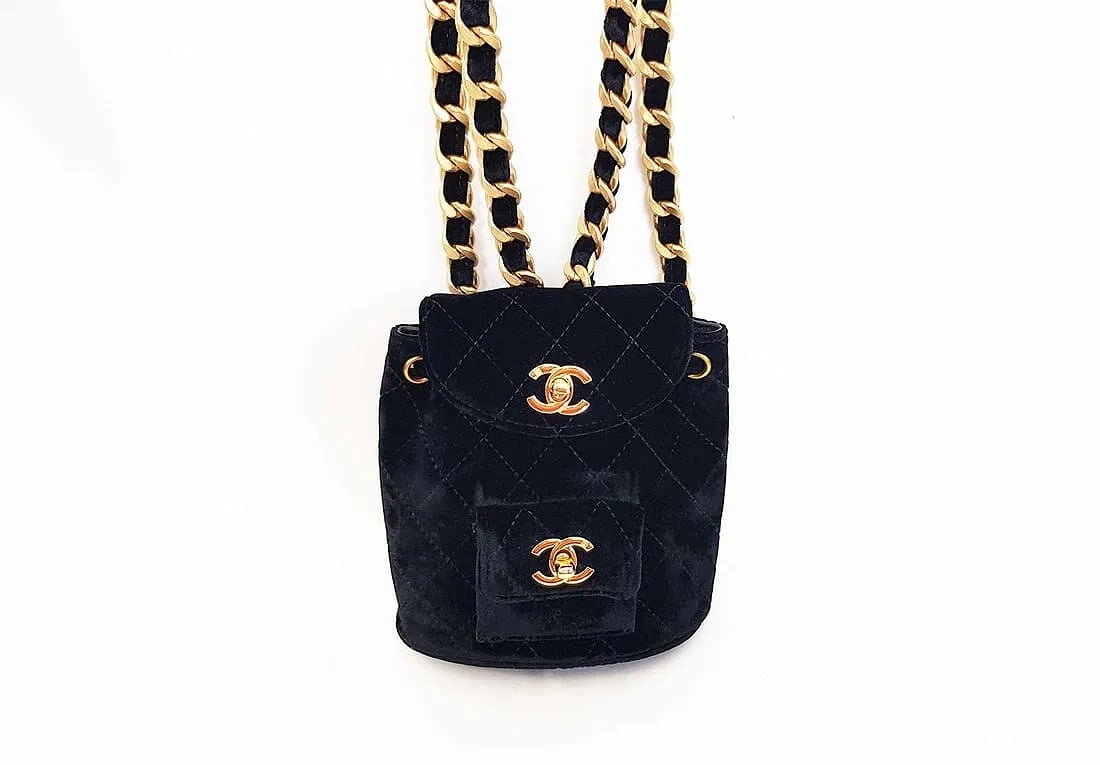 CHANEL Small Duma Backpack in Black Velvet w/ Diamond Quilting: CHANEL small Duma backpack in black velvet with diamond quilting. Features two fabric-and-chain shoulder straps, foldover top with drawstring fastening, and a front flap pocket, an iconic CHANEL backp