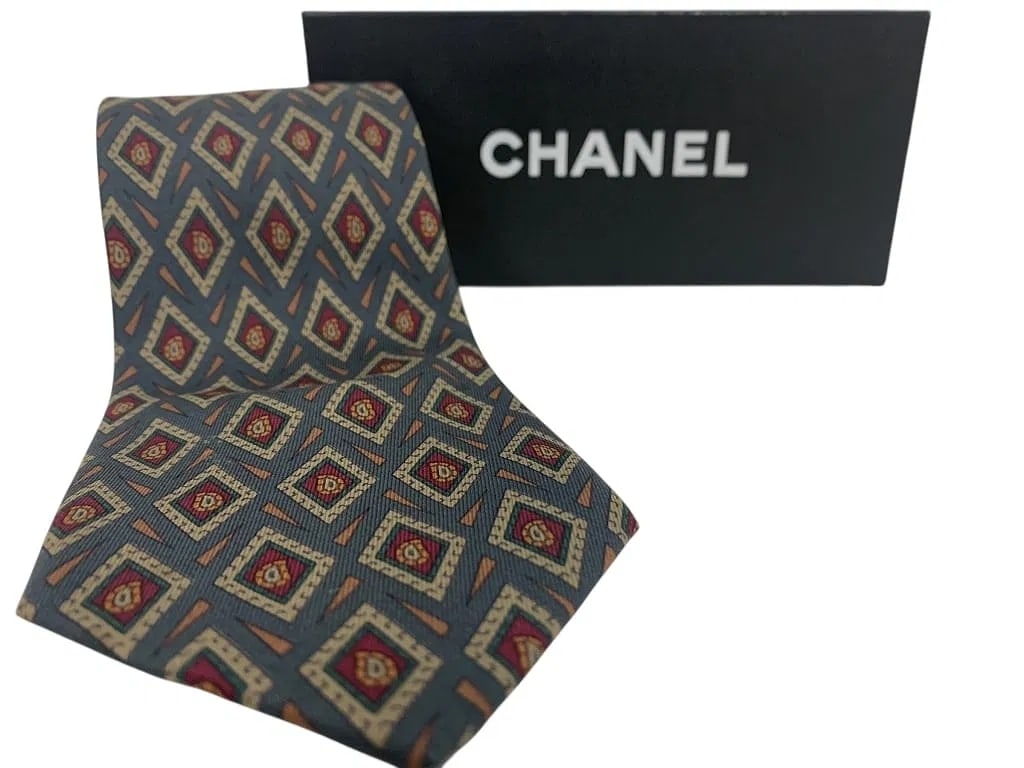CHANEL Silk Necktie w/ Slate/Steel Blue Ground & Repeating Geometric Diamond Motif Like New + Box: CHANEL men's silk tie featuring a slate/steel blue ground with a repeating geometric diamond motif in tones of red, gold, and ivory. Bold yet refined pattern that adds personality while staying polish