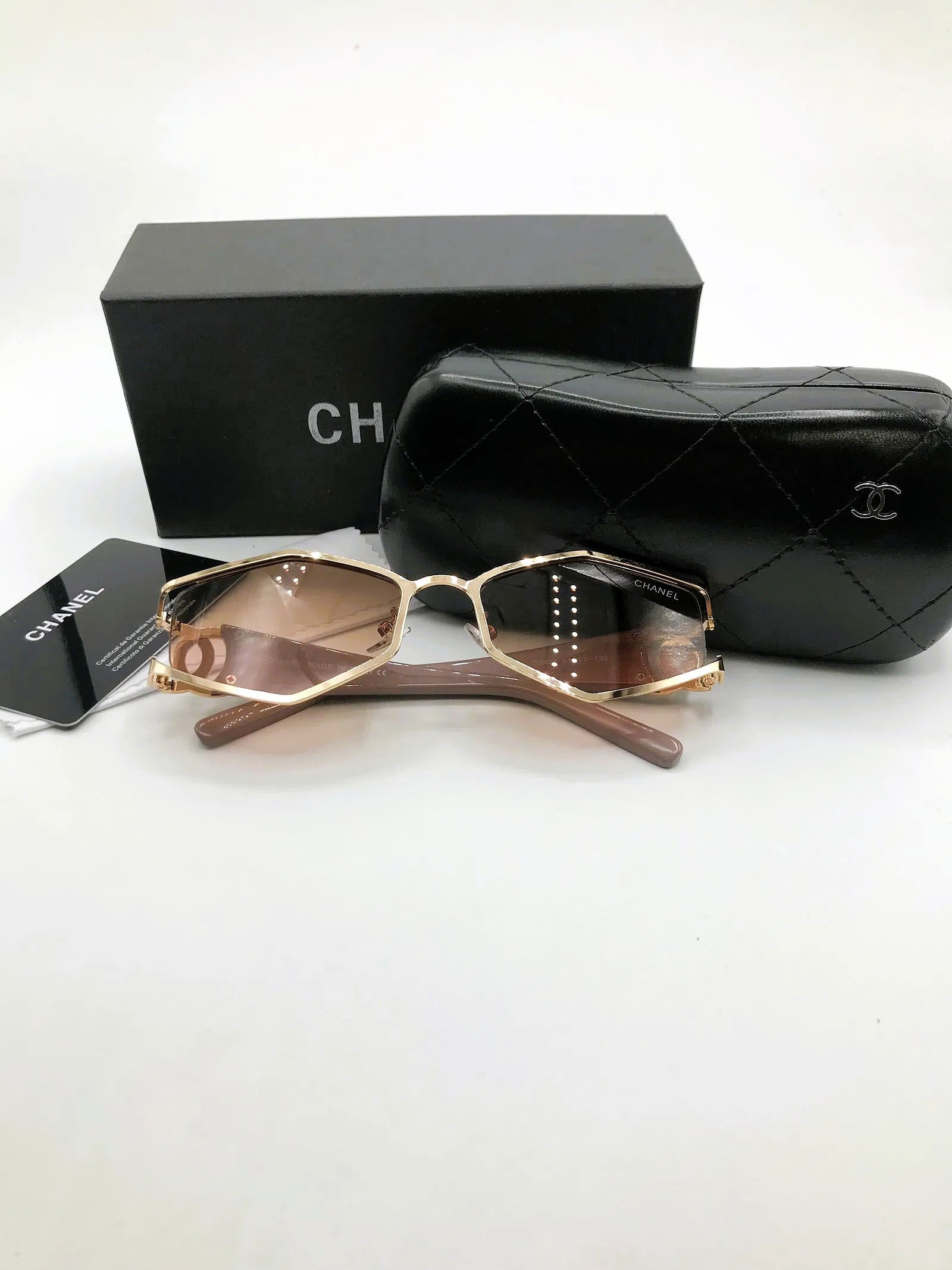 Chanel Gold Geometric Sunglasses w/ Quilted Case & Presentation Box: Geometric sunglasses marked Chanel, presented with quilted case and branded box as shown. This pair features an angular gold-tone metal frame fitted with brown gradient lenses and taupe temples. Inter