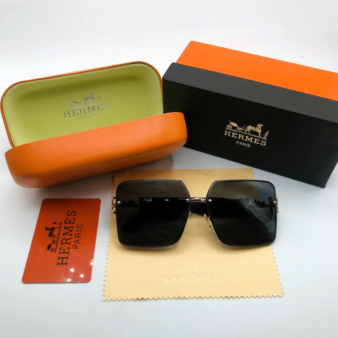 Hermès Oversized Square Sunglasses w/ Orange Case, Box & Cloth: Oversized square sunglasses marked Hermès, presented with orange clamshell case, box, cloth, and card as shown. This pair features large square dark lenses set within a gold-tone metal perimeter fram
