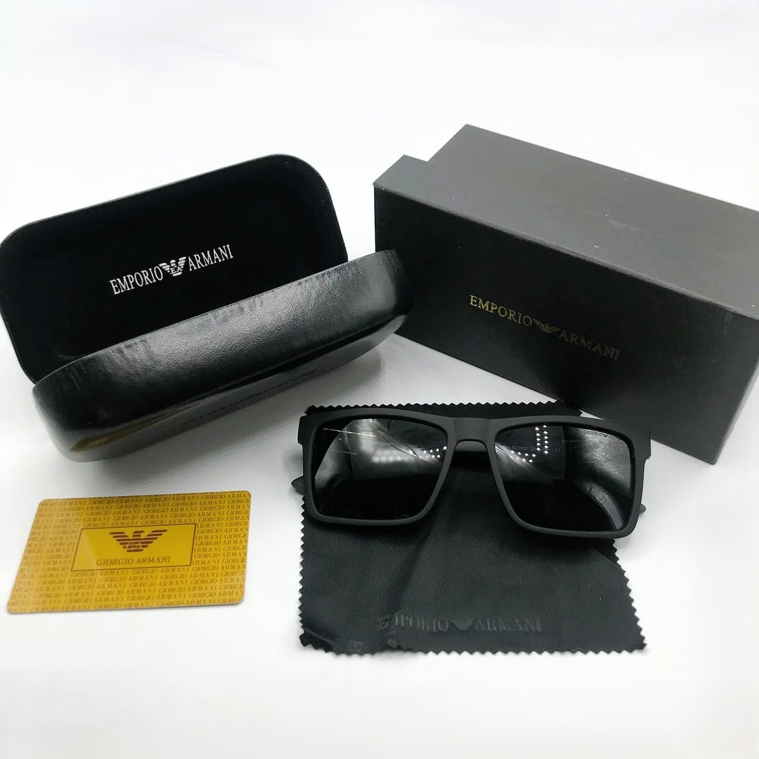 Emporio Armani Matte Black Square Sunglasses w/ Case, Box & Card: Square sunglasses marked Emporio Armani, presented with branded case, box, cloth, and card as shown. This pair features a matte black square frame with dark lenses and textured temple detailing. The E