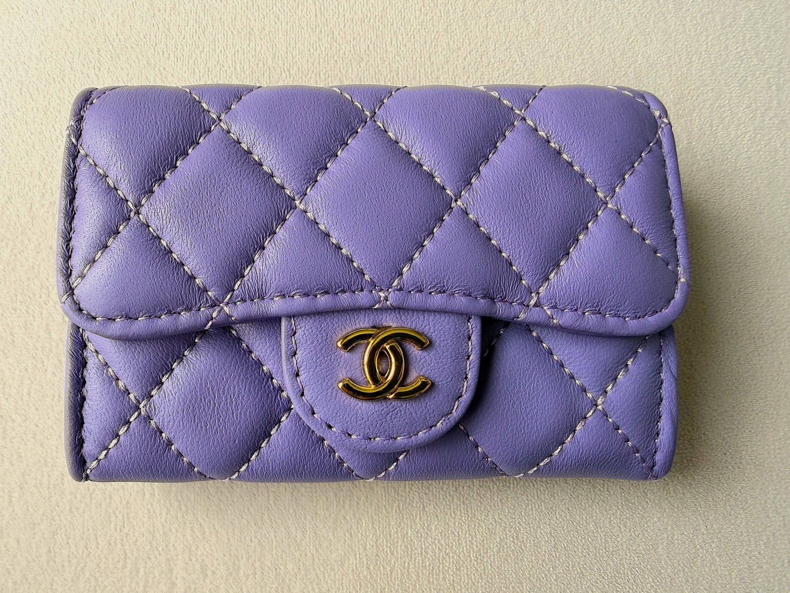 CHANEL Quilted Leather Flap Petite Wallet Lavender CC Snap w/ Dust Bag & box 4.5" x 3" x 1": Offered is a petite CHANEL quilted leather flap wallet/purse in a lavender/pastel purple tone with contrast stitching and gold-tone interlocking CC snap. The interior is lined in a deep burgundy texti