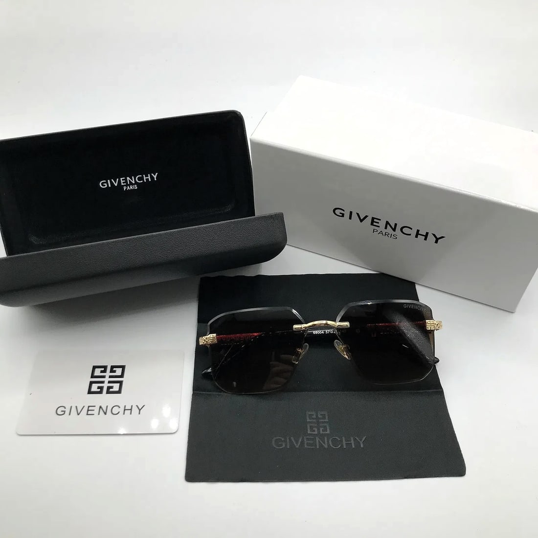 Givenchy Gold Rimless Shield Sunglasses w/ Case & Presentation Box: Rimless shield sunglasses marked Givenchy, presented with branded case and box as shown.This pair features a single-piece gradient lens set within gold-tone hardware, paired with black temples bearing