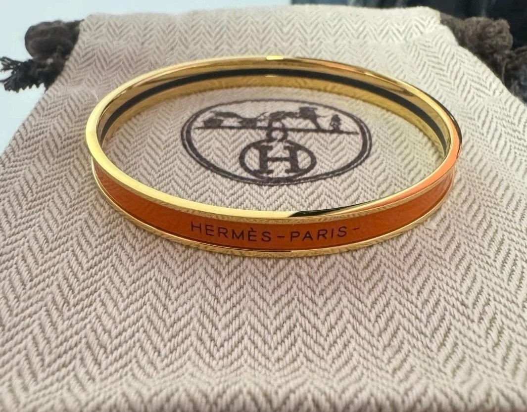 MSRP $1,395 HERMÈS Orange Enamel & Gold-Plated Bangle: Bright and iconic HERMÈS enamel bangle bracelet in orange with gold-plated metal, a standout color that instantly lifts neutral outfits and stacks beautifully. Includes pouch + box. Highlights 