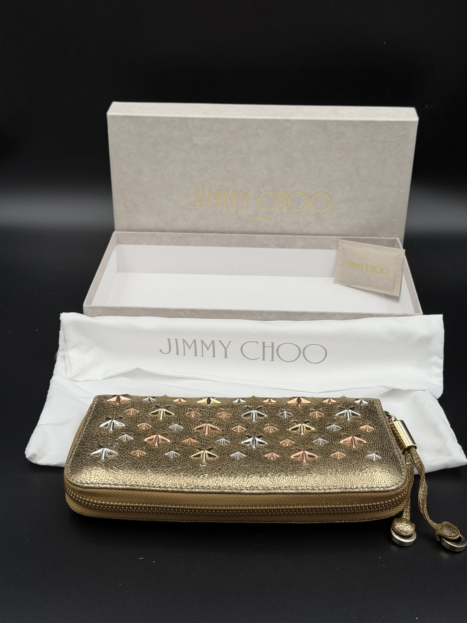 MSRP $1,250 JIMMY CHOO Filipa Zip Around Wallet Gold Metallic Stars Italy: Jimmy Choo Filipa zip-around wallet crafted in metallic gold leather featuring the house’s signature multicolor star-studded motif throughout. Designer continental wallet with zip-around constru