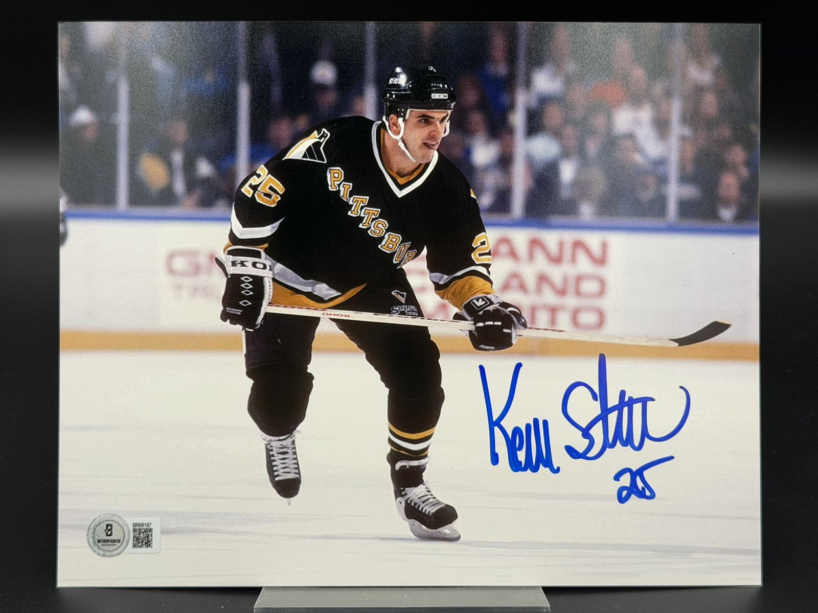 Autographed Kevin Stevens Pittsburgh Penguins 8" × 10" Photo Beckett COA: Color photograph personally signed by Pittsburgh Penguins standout Kevin Stevens in bold blue marker, adding his jersey number "25" beneath the signature. The action image captures Stevens skating in 