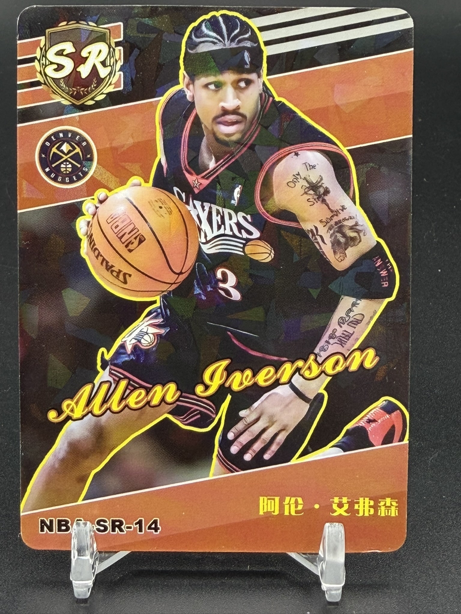 2023-24 Panini NBA Hoops Asia Allen Iverson SR-14 Super Rookie Denver Nuggets Basketball Card: Allen Iverson card #NB-SR-14 featuring the Hall of Fame guard in his Denver Nuggets uniform. This card showcases Iverson driving with a basketball on a reflective gold-accented background with his nam