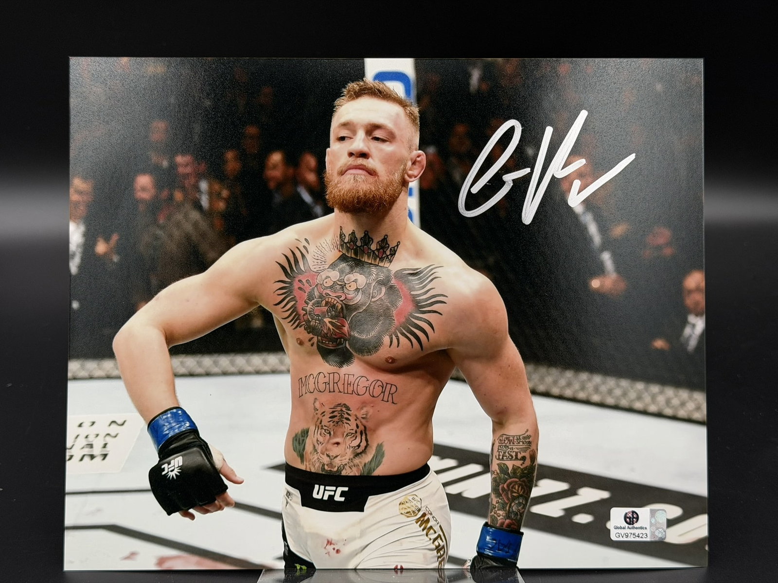 Conor McGregor Signed UFC MMA Photo GA COA 8" × 10": Color photograph personally signed by Conor McGregor in bold silver marker across the upper right corner. The striking image captures the former UFC MMA featherweight and lightweight champion inside t