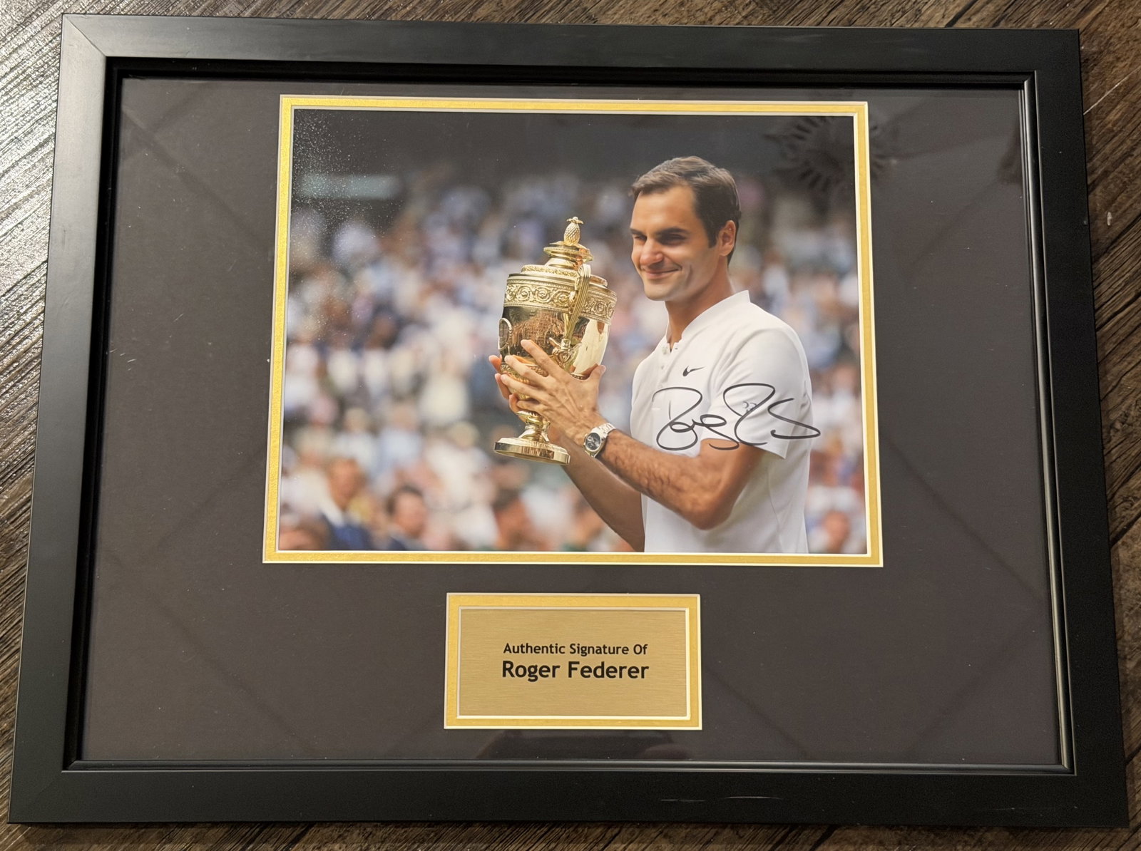 Autographed Roger Federer Framed Wimbledon Trophy Photo Display with COA: Professionally framed display featuring a color photograph personally signed by Roger Federer in black marker as he celebrates with the Wimbledon Gentlemen's Singles Trophy. The presentation includes 
