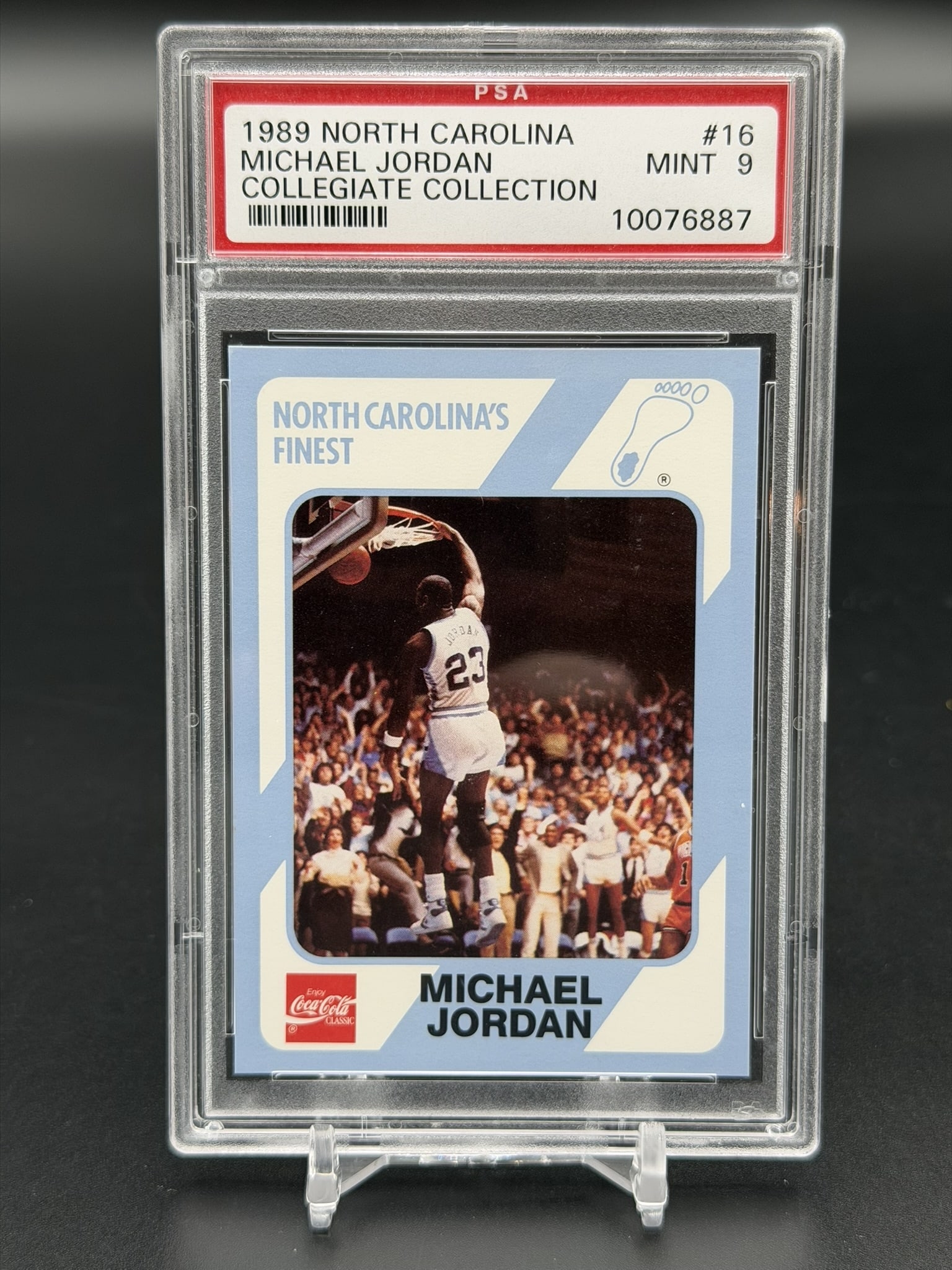1989 Collegiate Collection Michael Jordan North Carolina Finest #16 PSA 9 Mint Tar Heels Card: Vintage 1989 Collegiate Collection Michael Jordan North Carolina's Finest card #16, professionally graded PSA Mint 9. The front of this card features a collegiate action photograph of Jordan grasping 