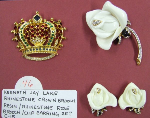 Kenneth Jay Lane Brooches: Grouping features a gold-tone crown brooch with green, blue, and red rhinestones and also includes an ivory resin rose brooch with studded stem and matching clip-on earrings.