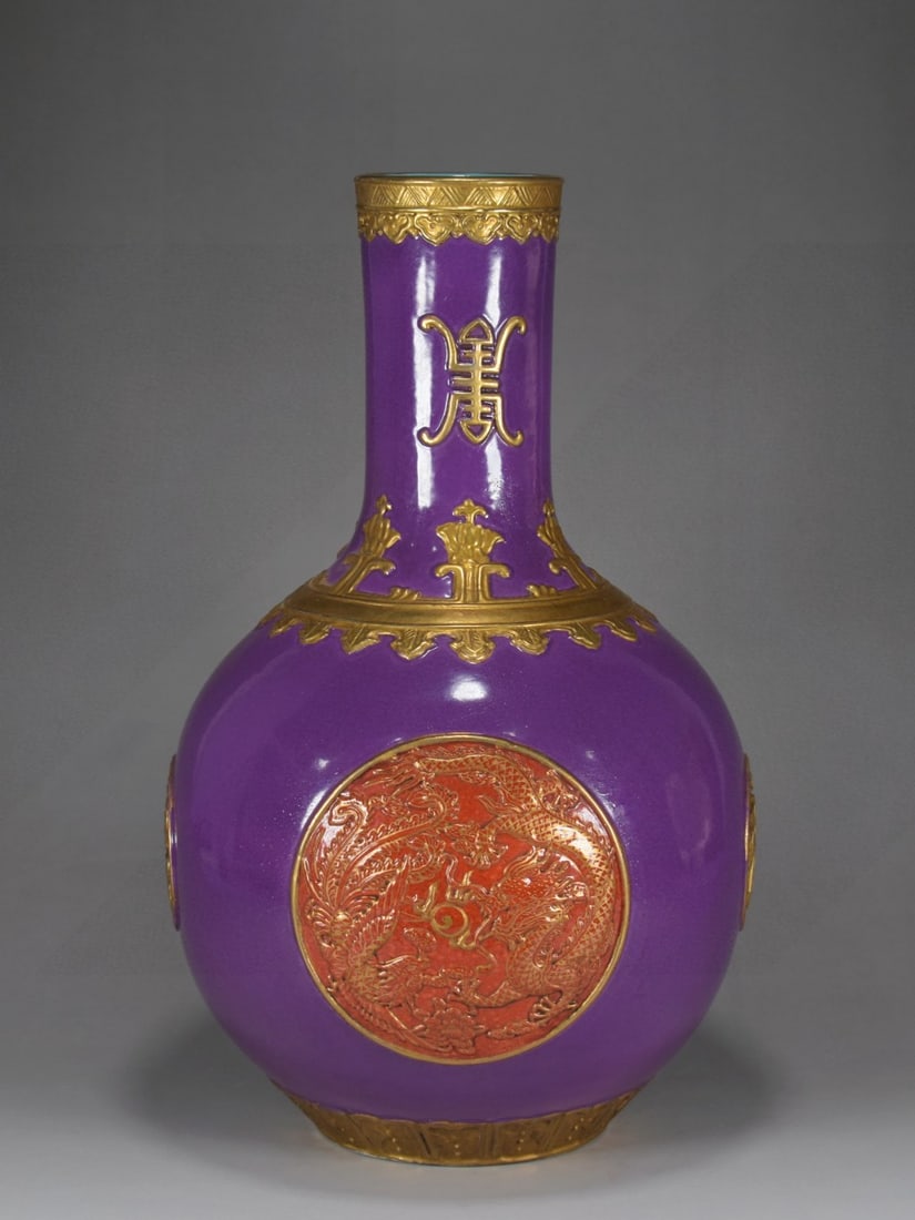 A large Qing Dynasty Qianlong period eggplant-purple glazed gilt-carved four-window dragon and: Made during the Qianlong reign of the Qing Dynasty, this eggplant-purple glazed, gilded, carved four-pane vase depicting dragons and phoenixes symbolizing good fortune and longevity. Provenance:The Pr