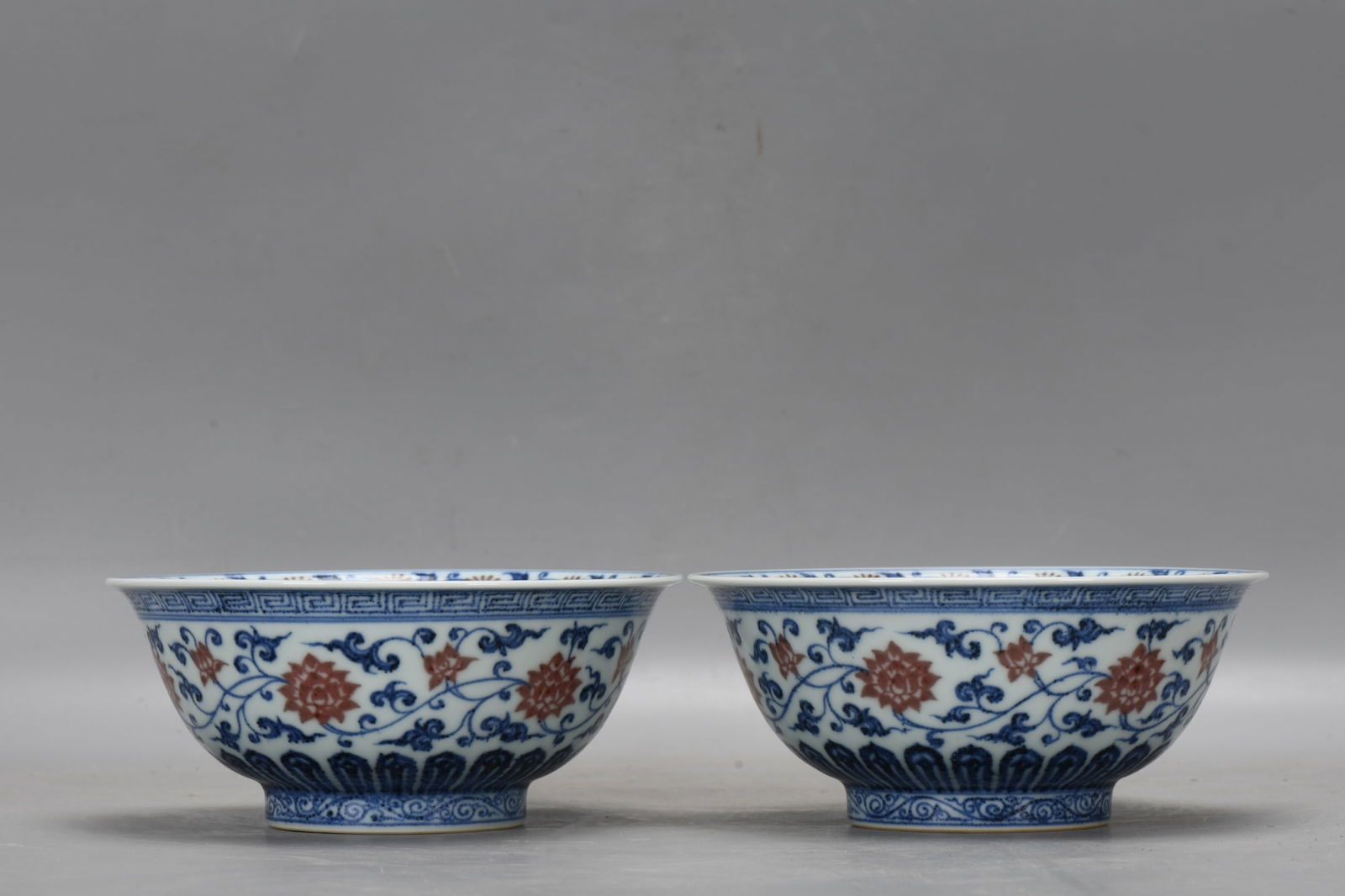 A pair of Ming Dynasty Xuande blue and white underglaze red lotus scroll bowls: A pair of Ming Dynasty Xuande blue and white underglaze red lotus scroll bowls, 7.5 cm high, 17.5 cm in diameter at the mouth, and 8 cm in diameter at the base. Provenance:An old private collection in