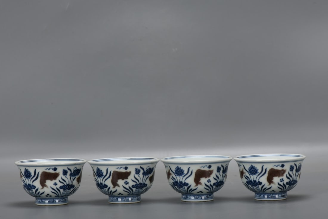 A set of Ming Dynasty Xuande blue and white underglaze red fish and grass pattern hand-pressed cups: A set of blue and white underglaze red fish and grass pattern cups from the Xuande period of the Ming Dynasty. The cups are 5.3 cm high, 9.3 cm in diameter at the mouth, and 4 cm in diameter at the ba