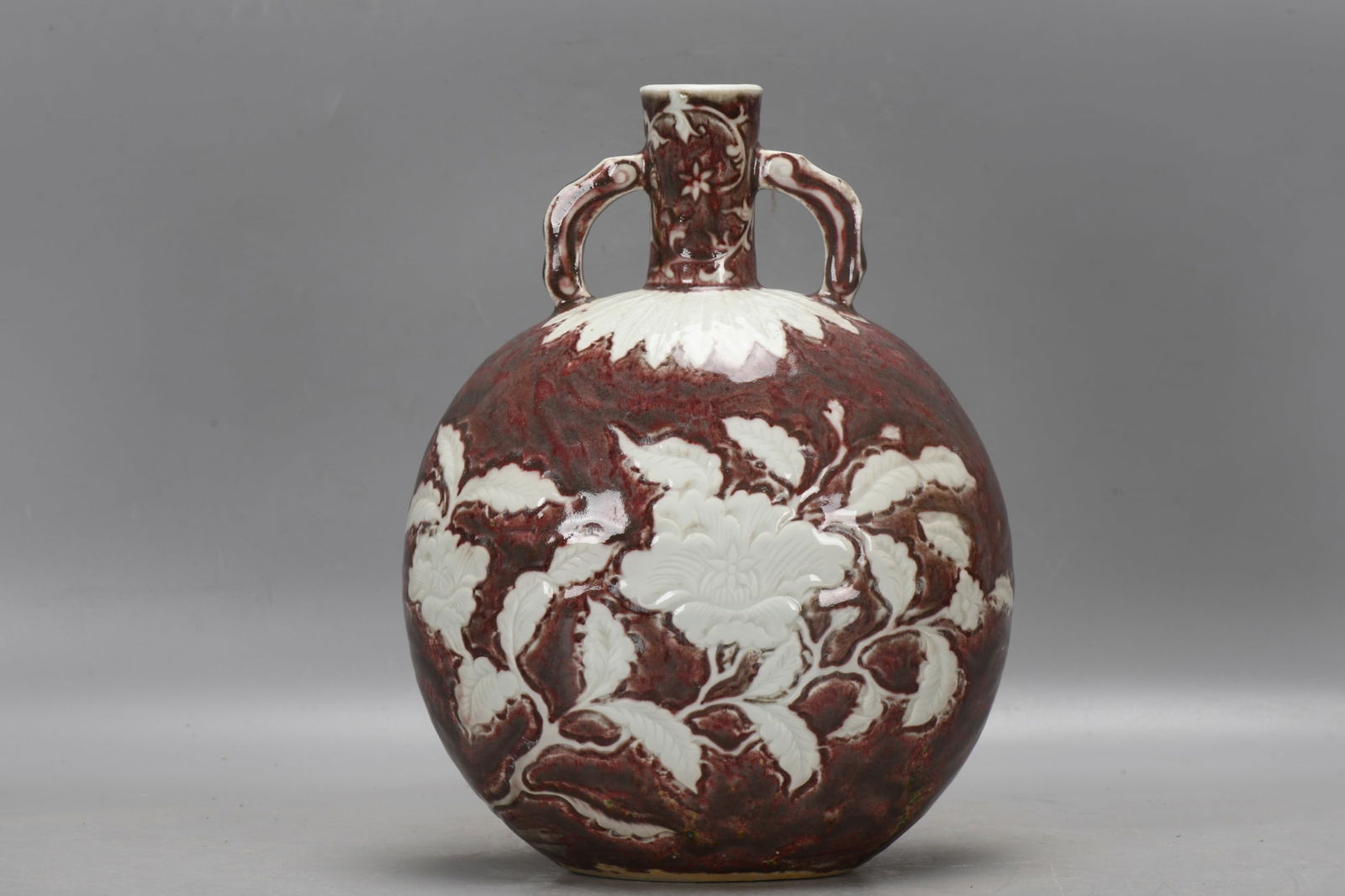 A Ming Dynasty, Yongle period underglaze red moon flask with carved floral designs in white space. (1 of 9)