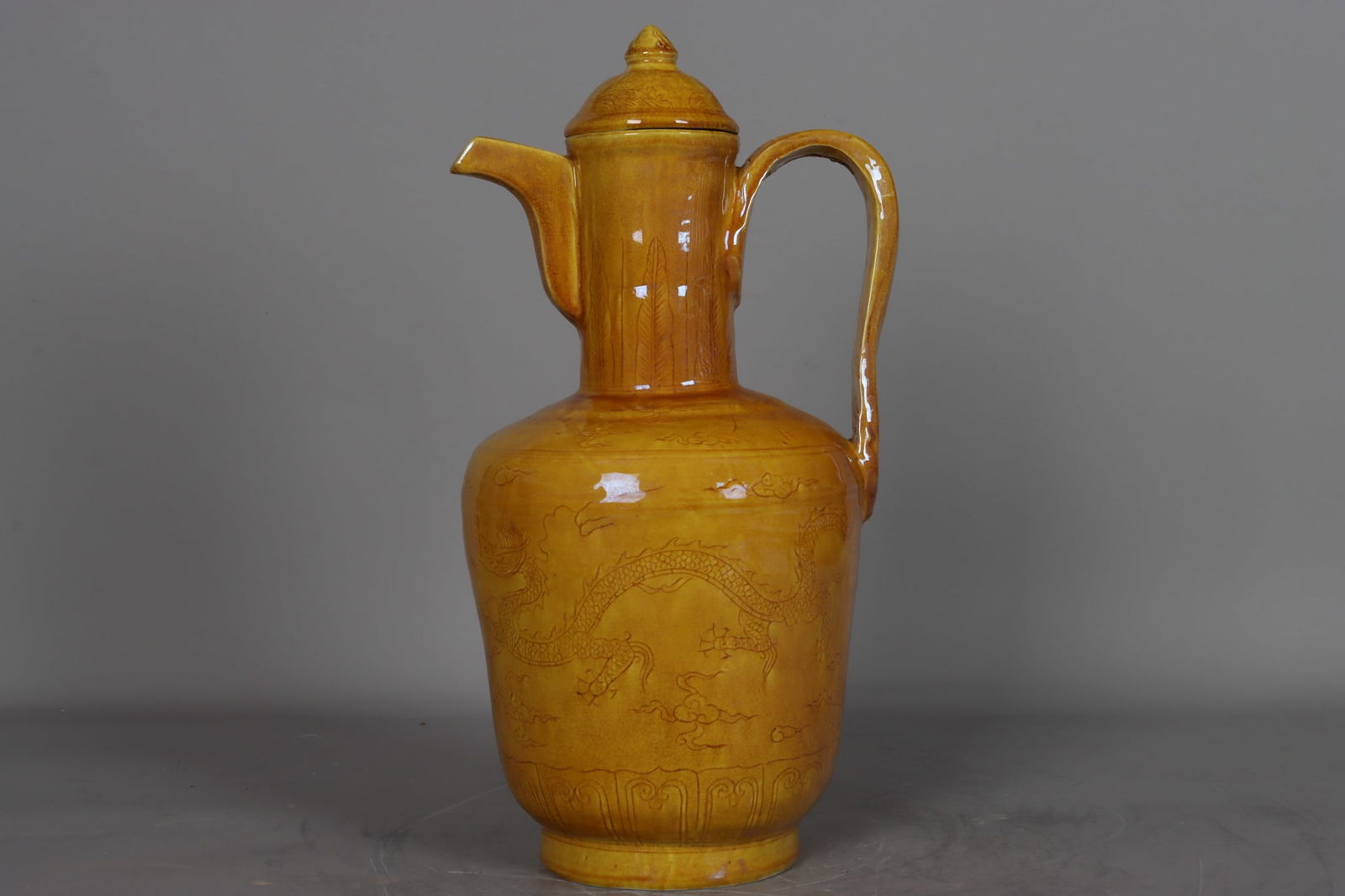 A Ming Dynasty, Hongzhi period yellow-glazed carved dragon, phoenix, and cloud pattern ewer: A Ming Dynasty (Hongzhi period) yellow-glazed carved dragon, phoenix, and cloud pattern ewer, 36 cm high, 7.5 cm in mouth diameter, 18 cm in belly diameter, and 11.5 cm in base diameter. Provenance:Th