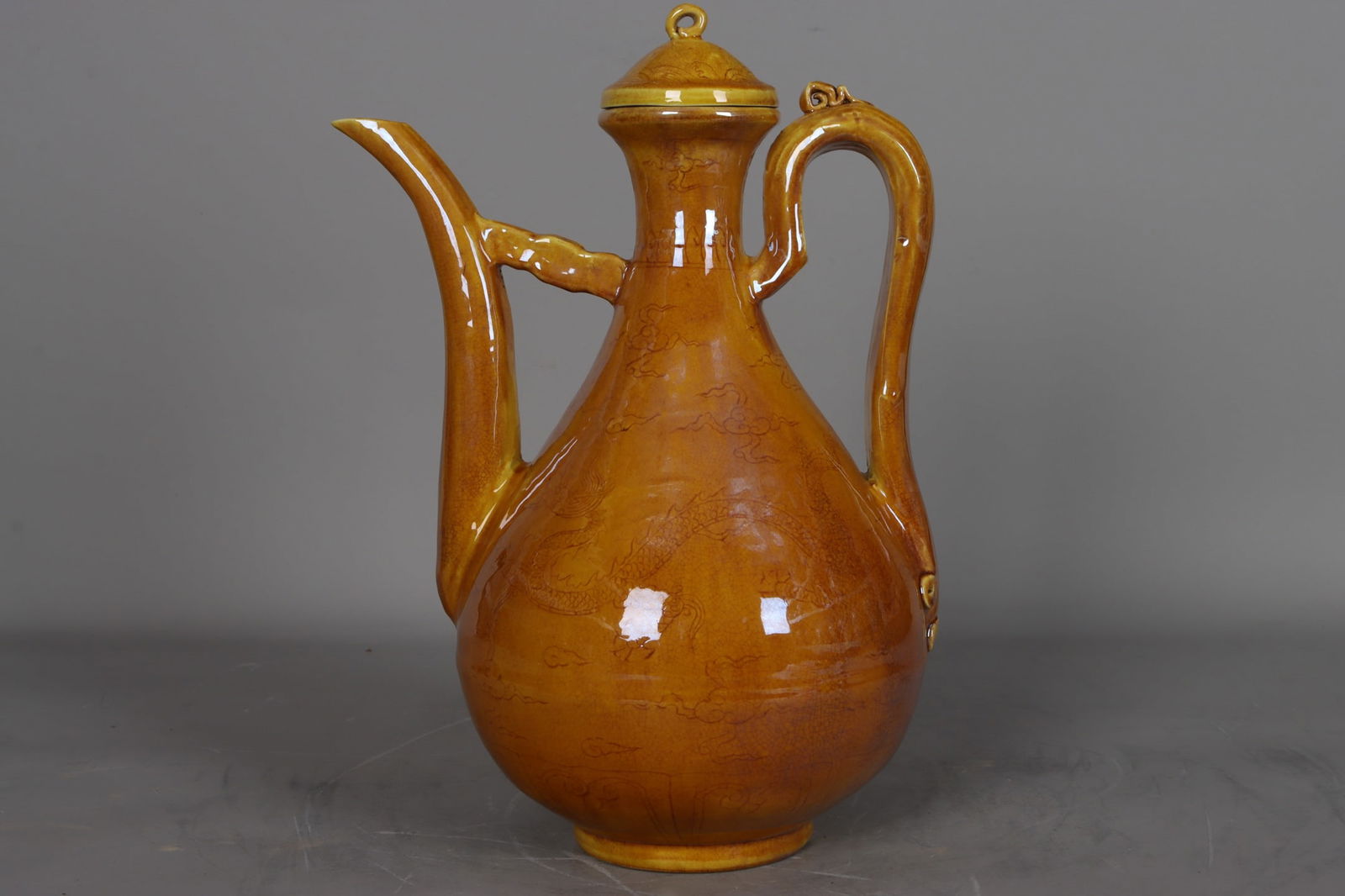 A Ming Dynasty, Hongzhi period yellow-glazed ewer with carved dragon, phoenix, and cloud patterns.: A Ming Dynasty (Hongzhi period) yellow-glazed ewer with carved dragon, phoenix, and cloud patterns, measuring 31.5 cm in height, 6.5 cm in mouth diameter, 18.5 cm in belly diameter, and 9 cm in base d