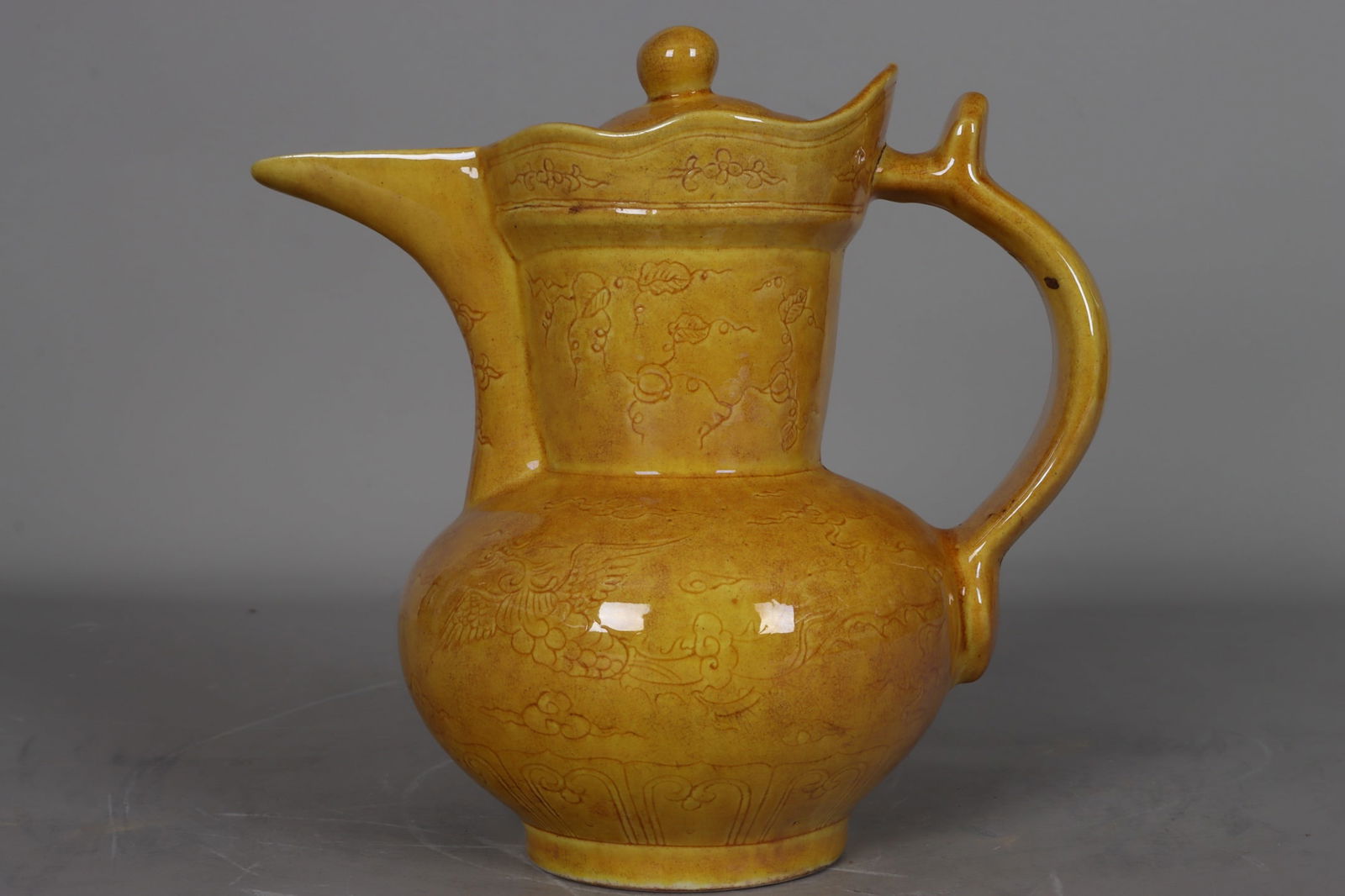A Ming Dynasty, Hongzhi period yellow-glazed carved double phoenix and floral Zeng-style hat-shaped: Ming Dynasty (Hongzhi period) yellow-glazed carved double phoenix and floral Zeng-style hat-shaped ewer, 22 cm high, 16 cm in mouth diameter, 23 cm in belly diameter, and 8 cm in base diameter. Proven