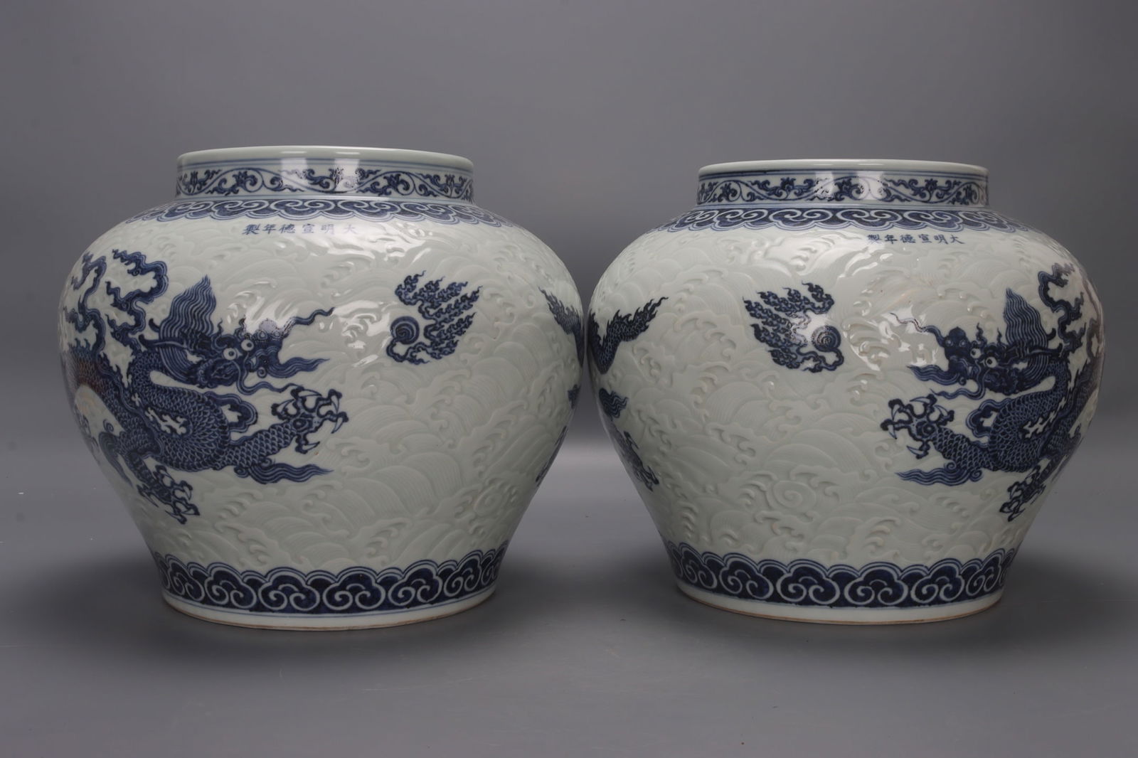 A pair of Ming and Xuande blue and white porcelain jars carved with dragons and clouds. (1 of 9)