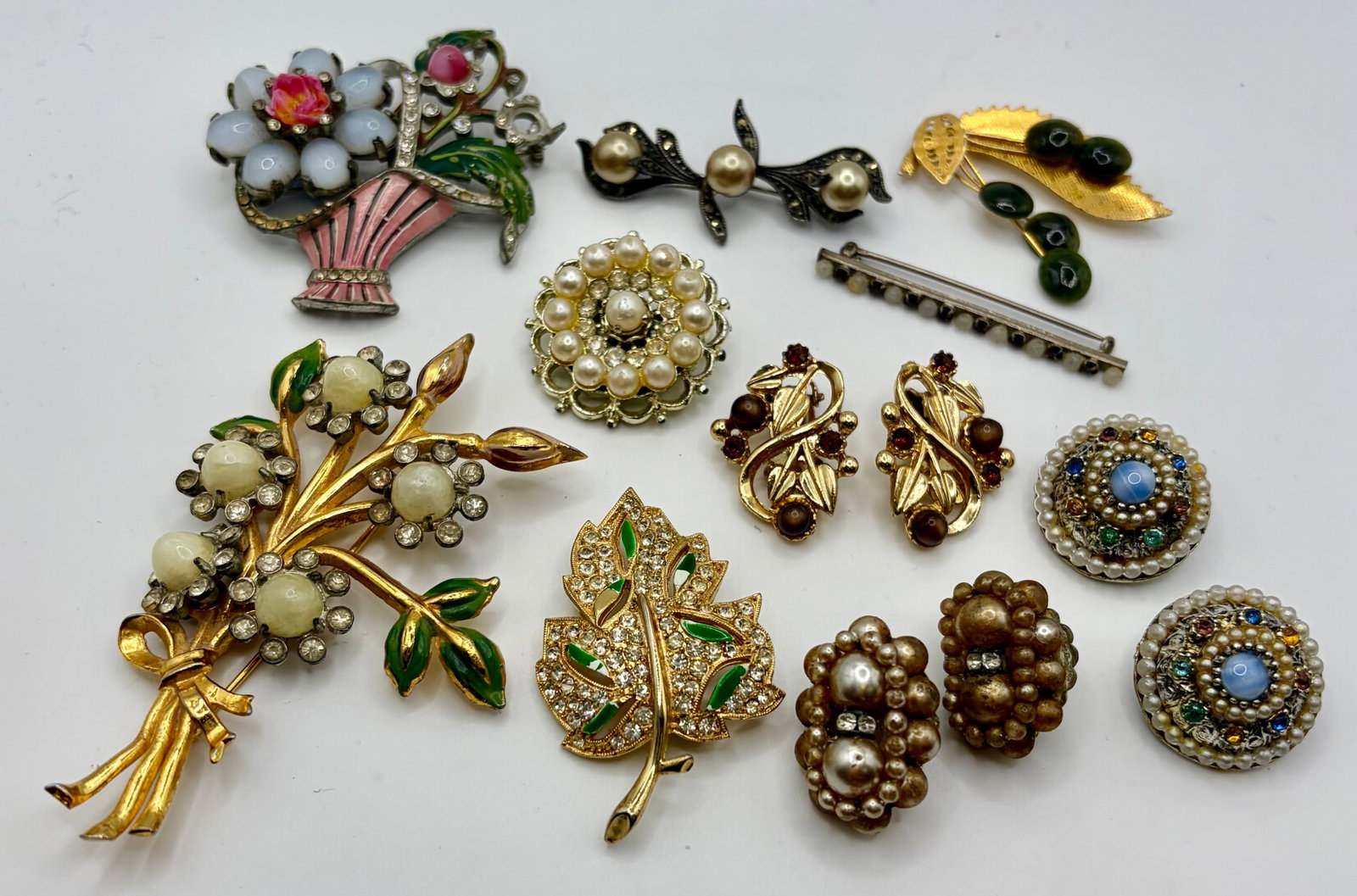 Collection of Vintage Costume Jewelry: This vintage collection of costume jewelry includes three pairs of clip earrings and seven brooches/pins. All of the pieces feature faux pearls, rhinestones, and/or faux stones. The largest brooch (th