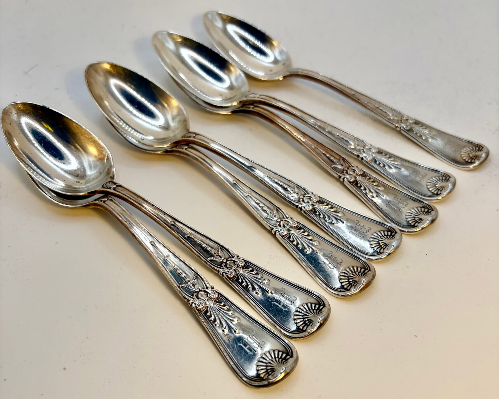 Seven Sterling Silver Kirkpatrick Spoons: A set of seven sterling silver spoons with a monogram and shell motif. Each spoon measures 6” long and the weights vary from 32.0 grams to 34.0 grams. The average weight 33.48 grams each and tot