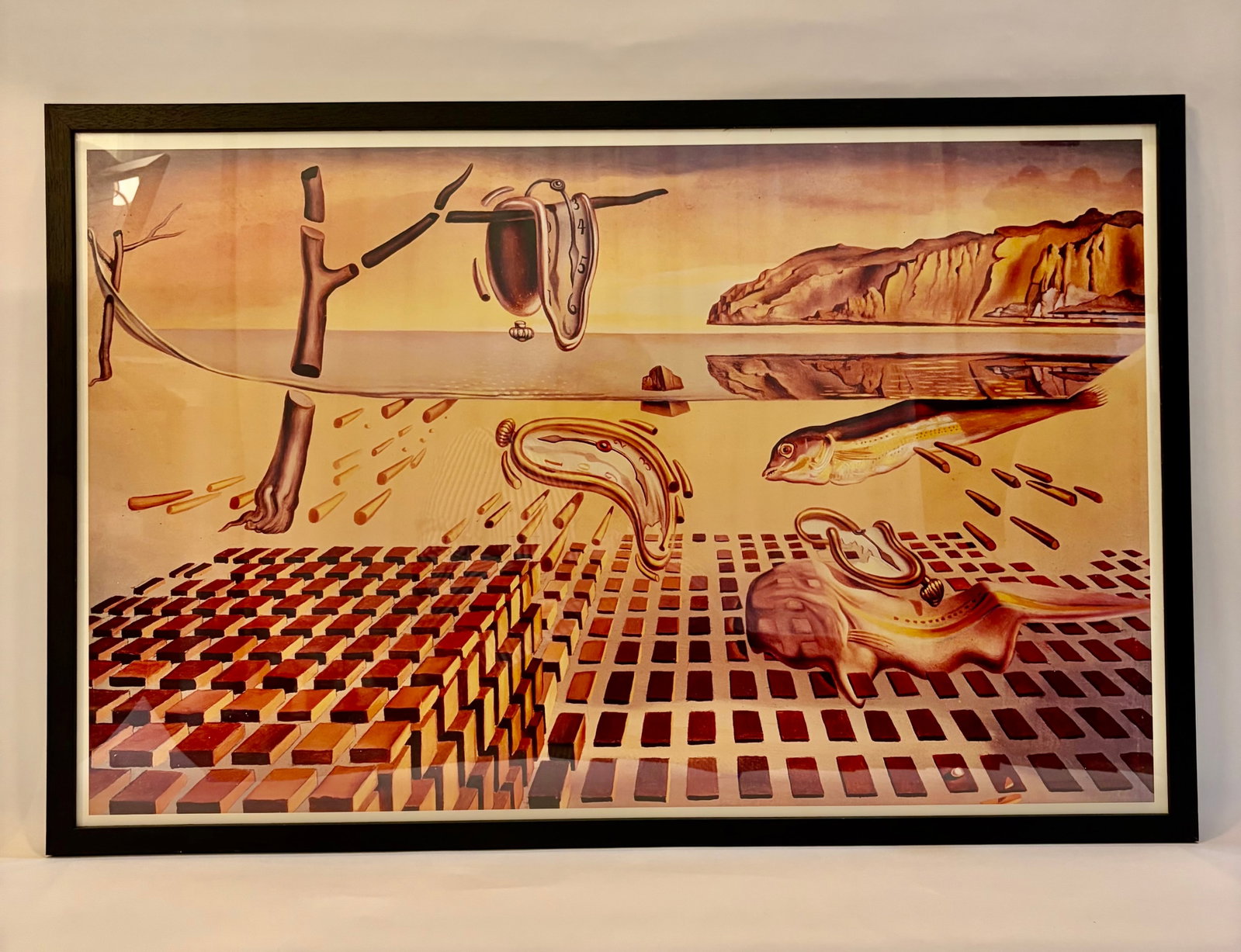 Framed Salvador Dali “The Persistence of Memory”: A nicely framed poster of Salvador Dali’s ‘Persistence of Memory’. The poster is presented in a black painted wood frame with a 1/2” white boarder & under glass. The back is fi